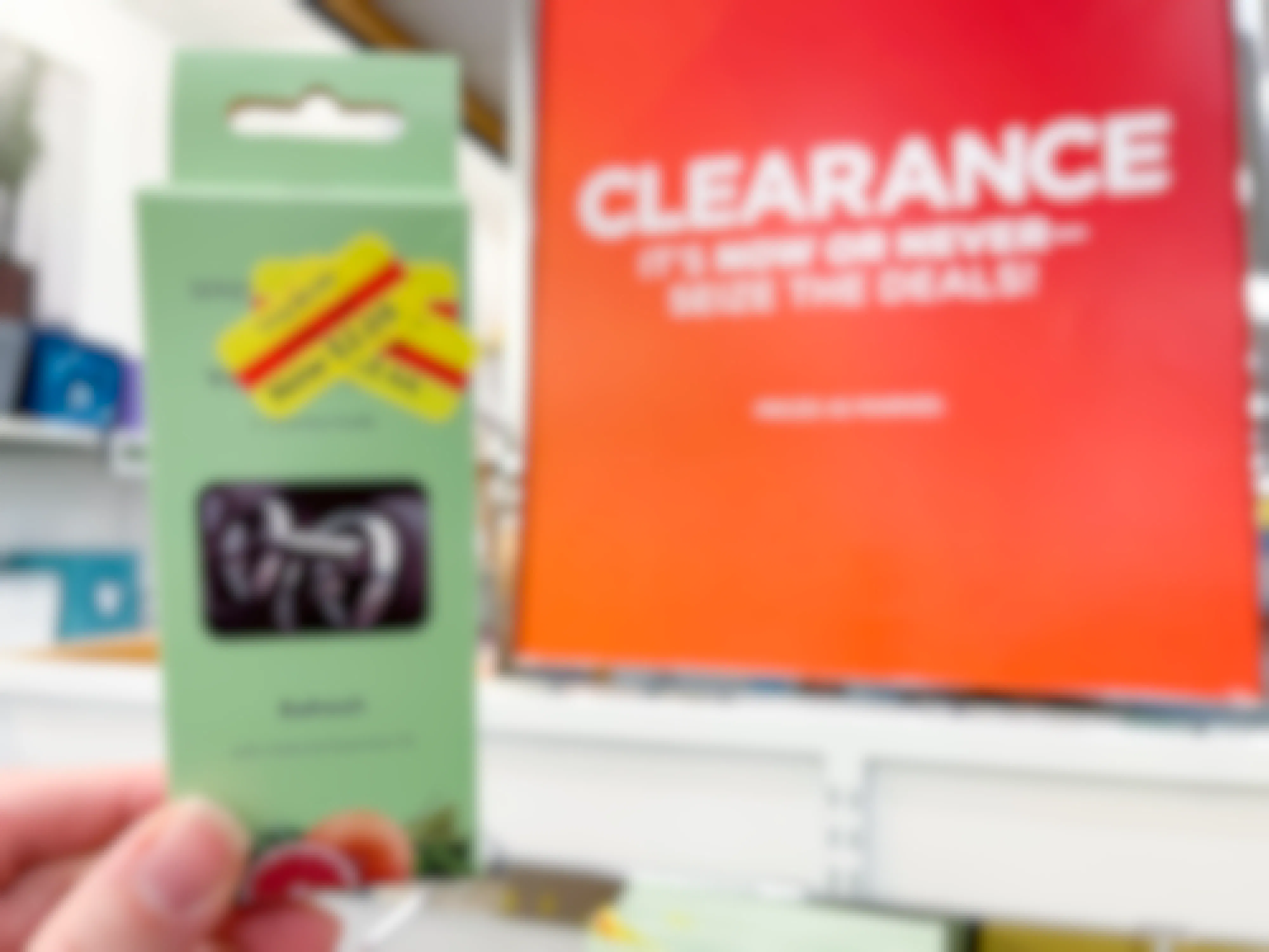 A bunch of clearance stickers on the front of a package held up next to a clearance sign.