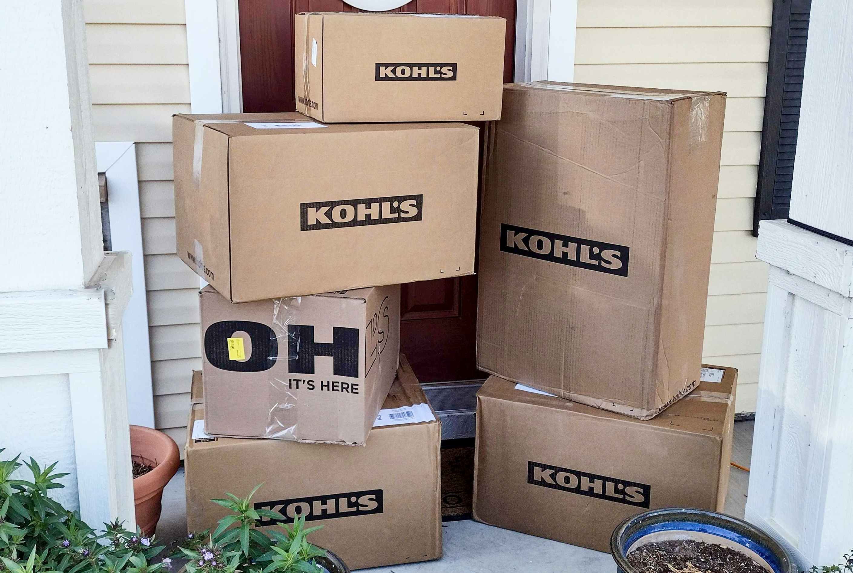 A stack of Kohl's delivery boxes sitting on a front porch.