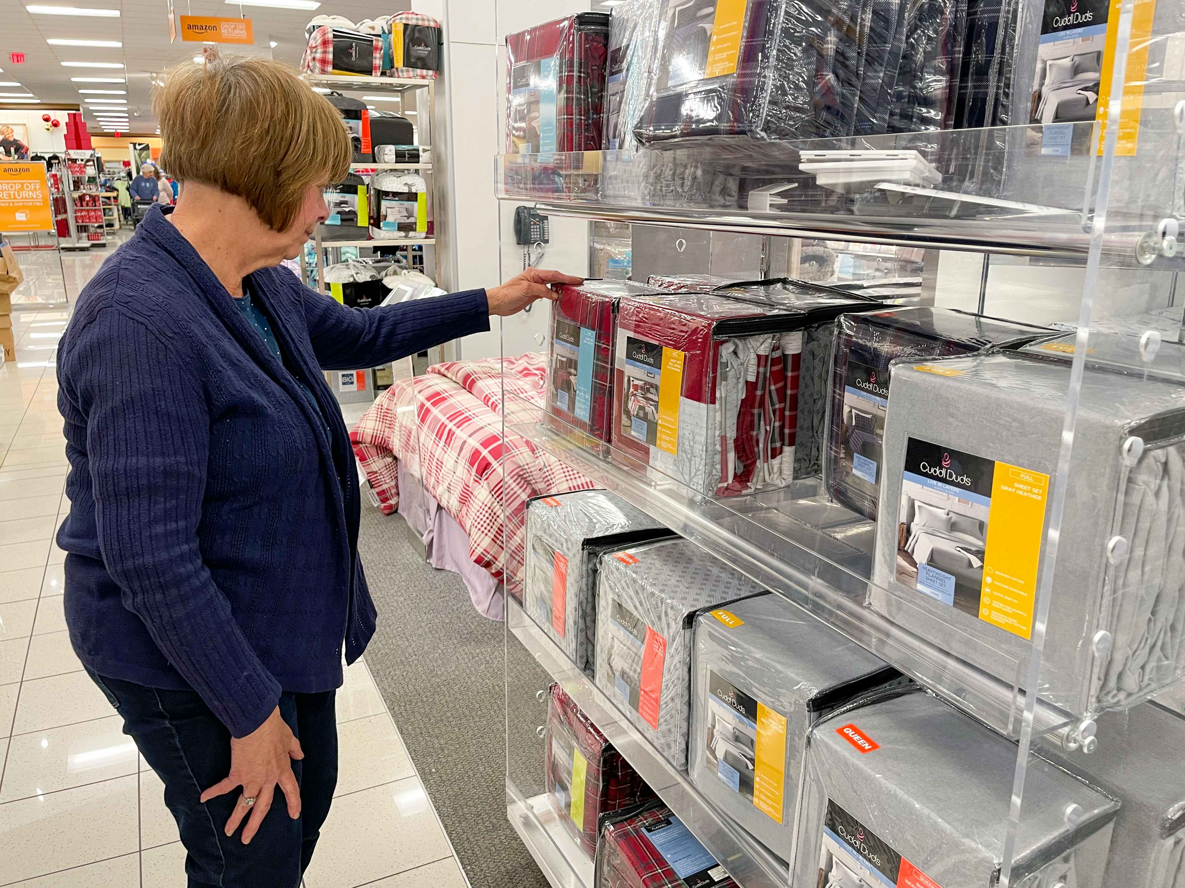 A woman looking at bed sheets inside Kohls