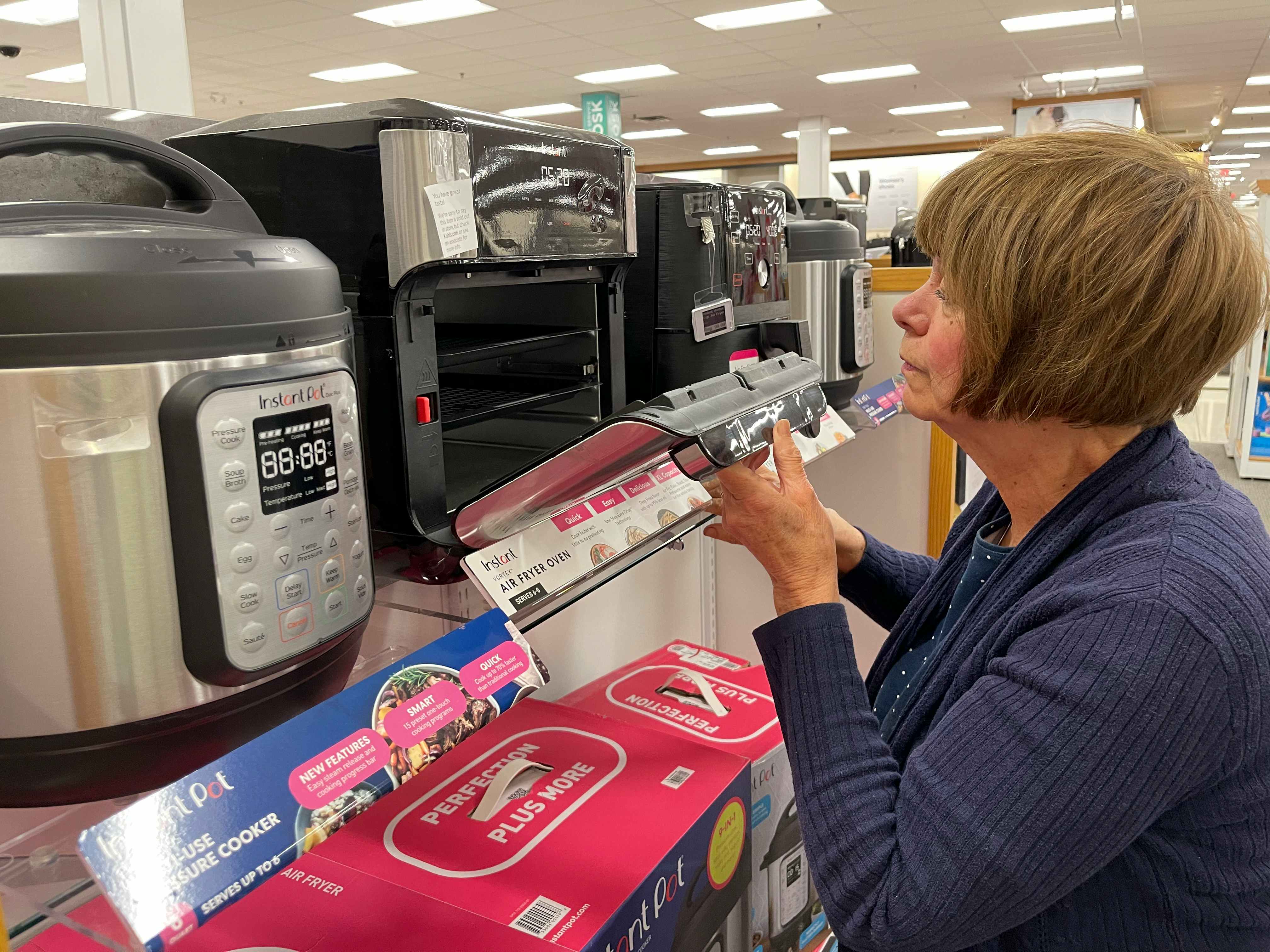 A woman looking at Instant air fryer machines at Kohl's