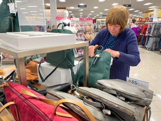 A senior woman looking at purses inside Kohls.
