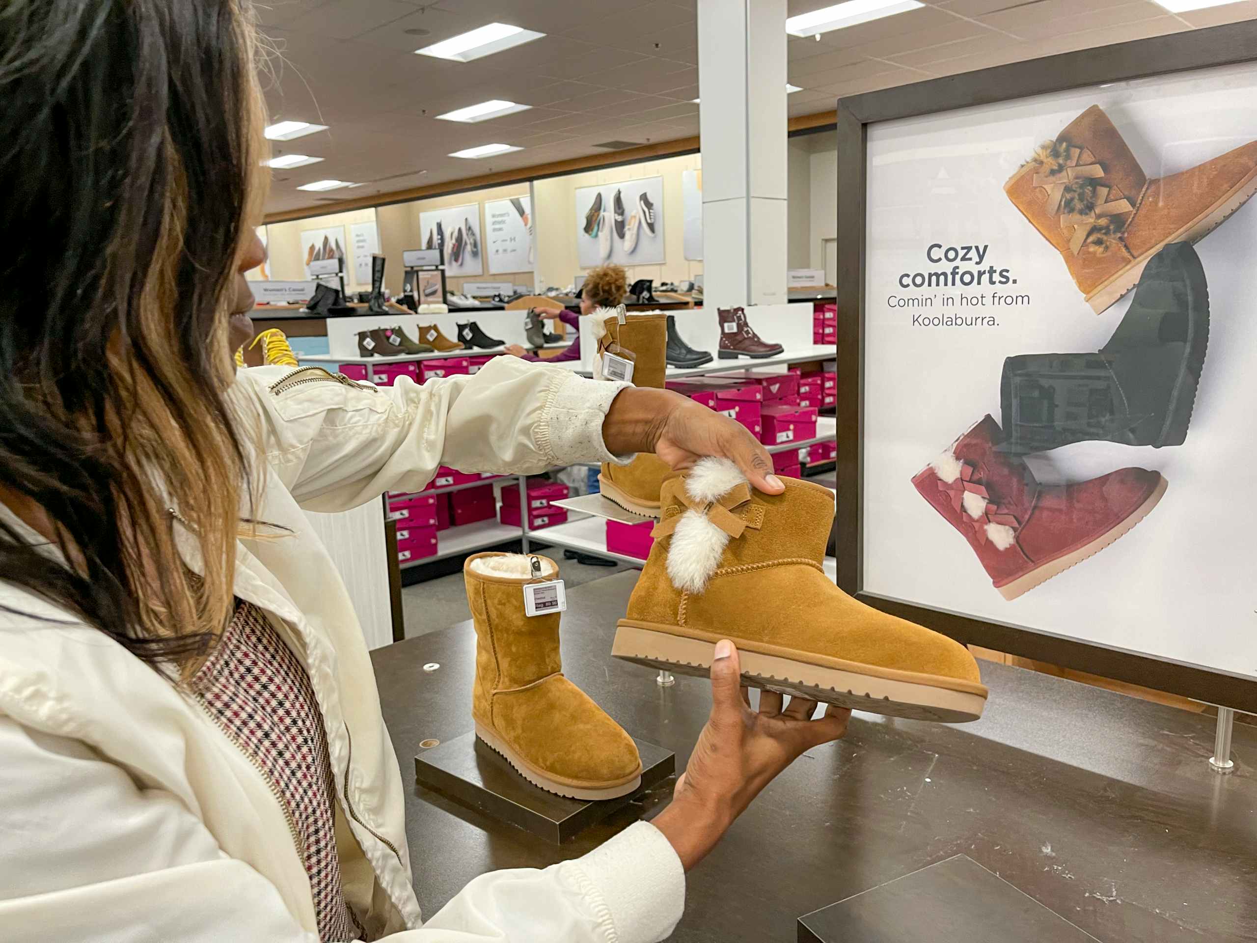 A woman looking at boots inside Kohls