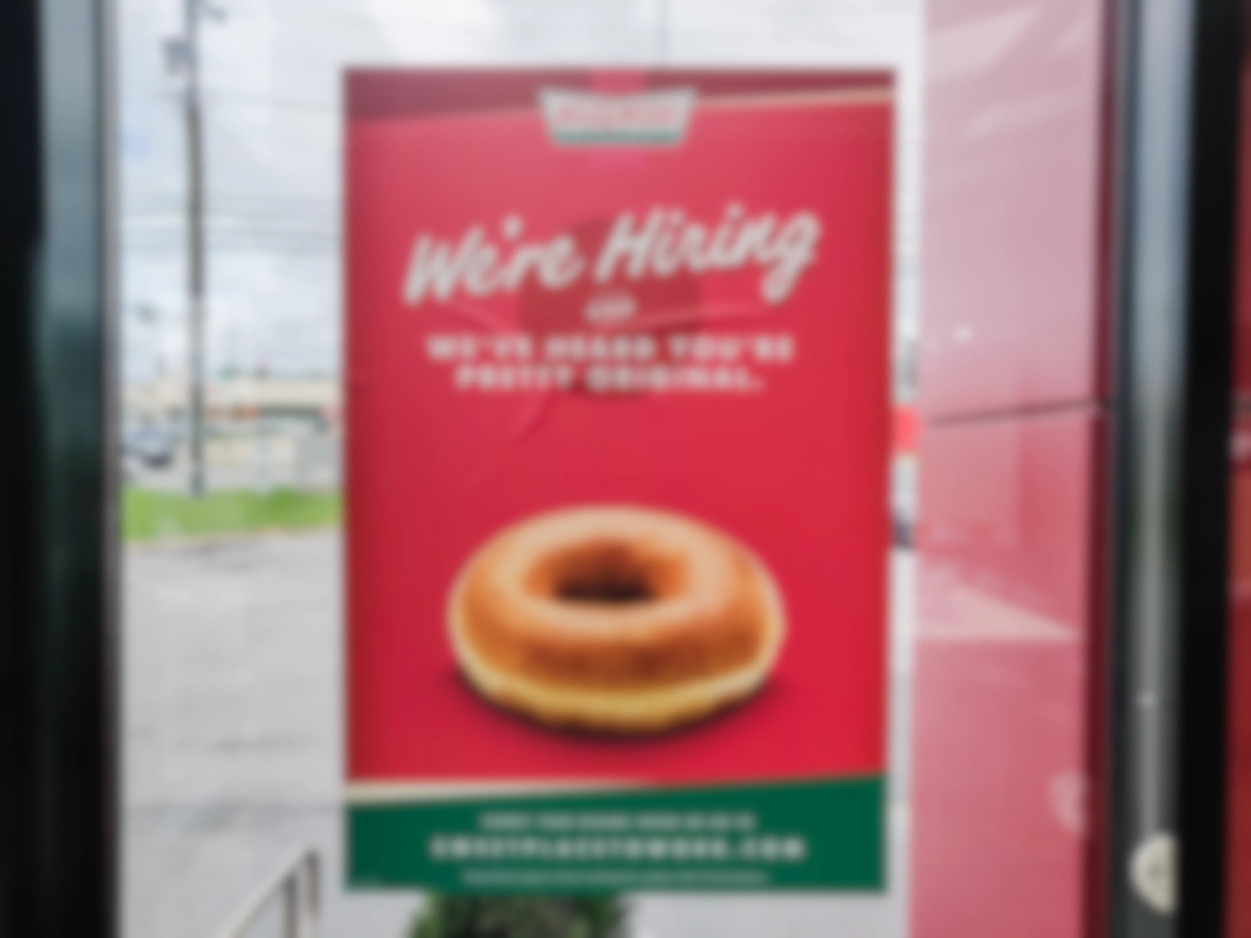 A "We're Hiring" sign on a Krispy Kreme door.