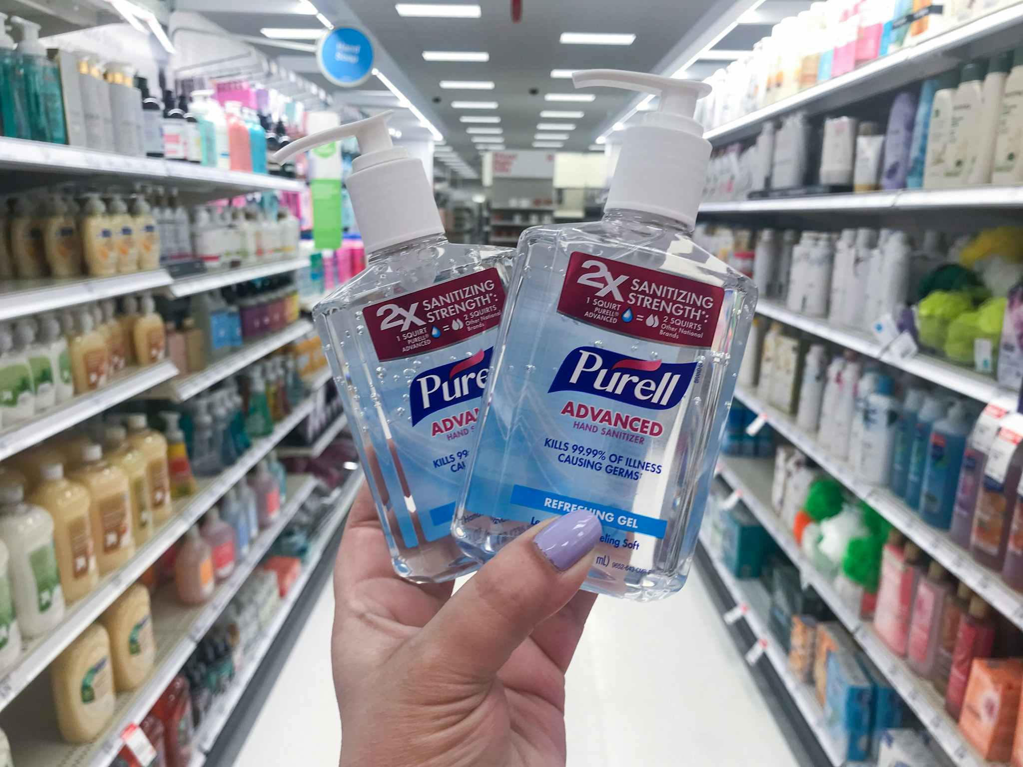 hand holding two bottles of purell hand sanitizer at target