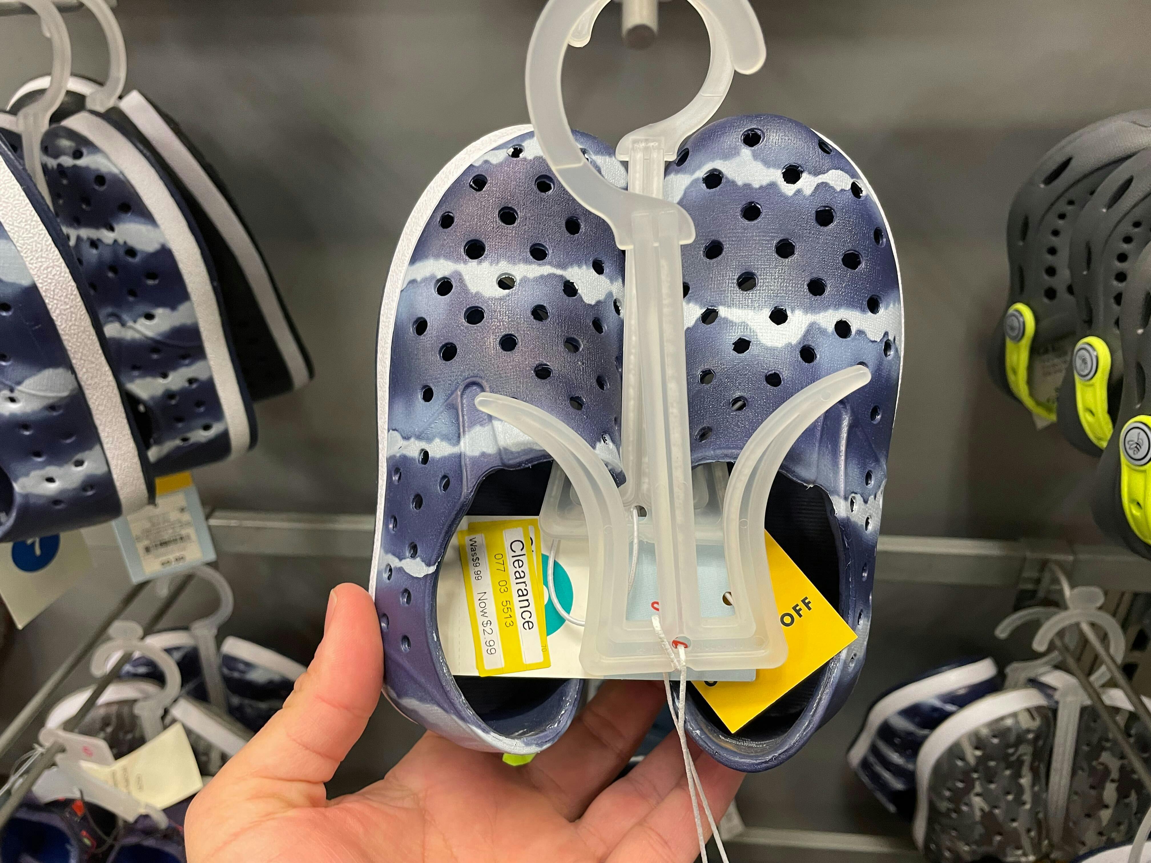 A person's hand taking a pair of Crocs Dupes on clearance at Target.