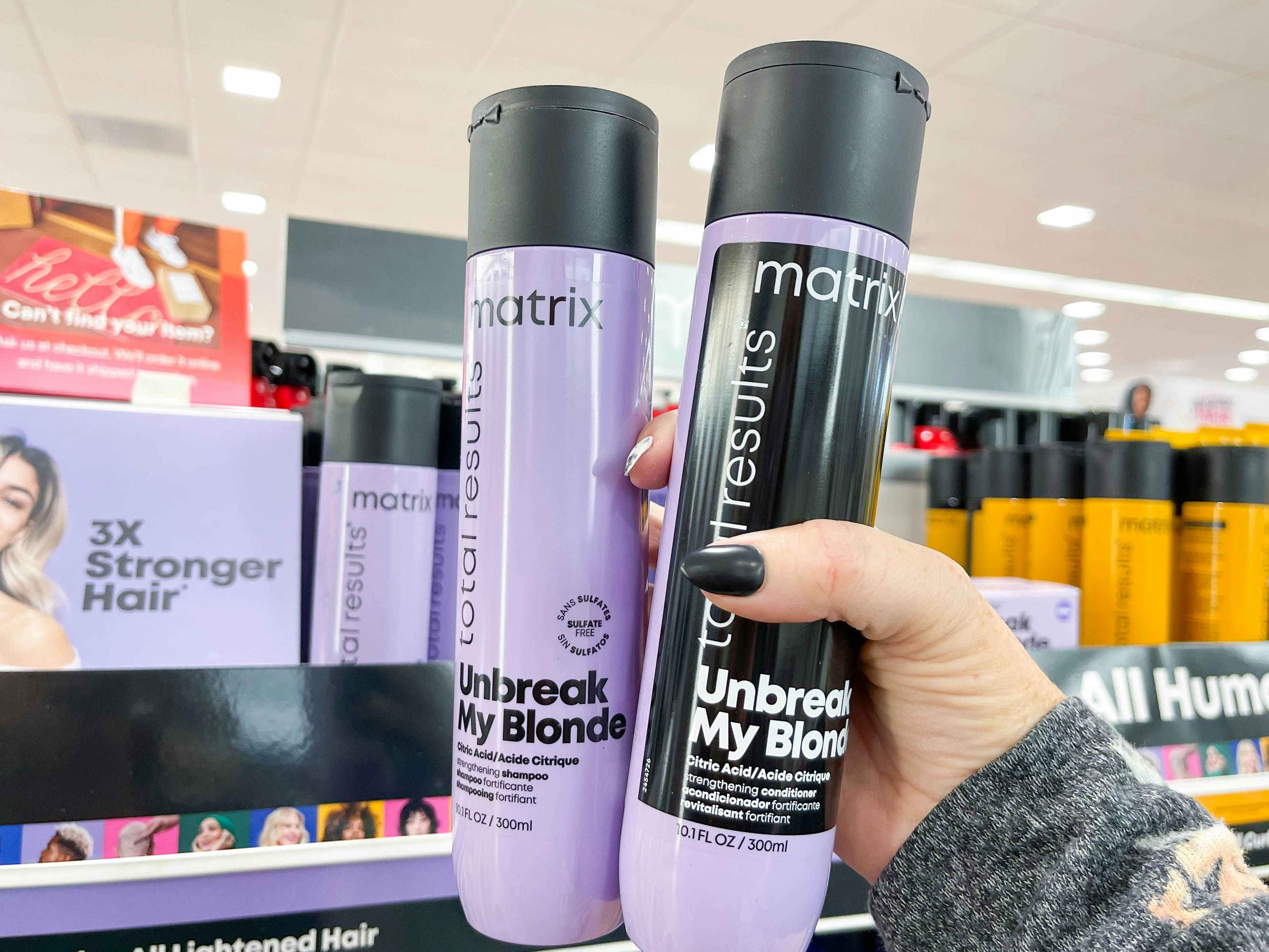 matrix shampoo and conditioner being held in front of shelf