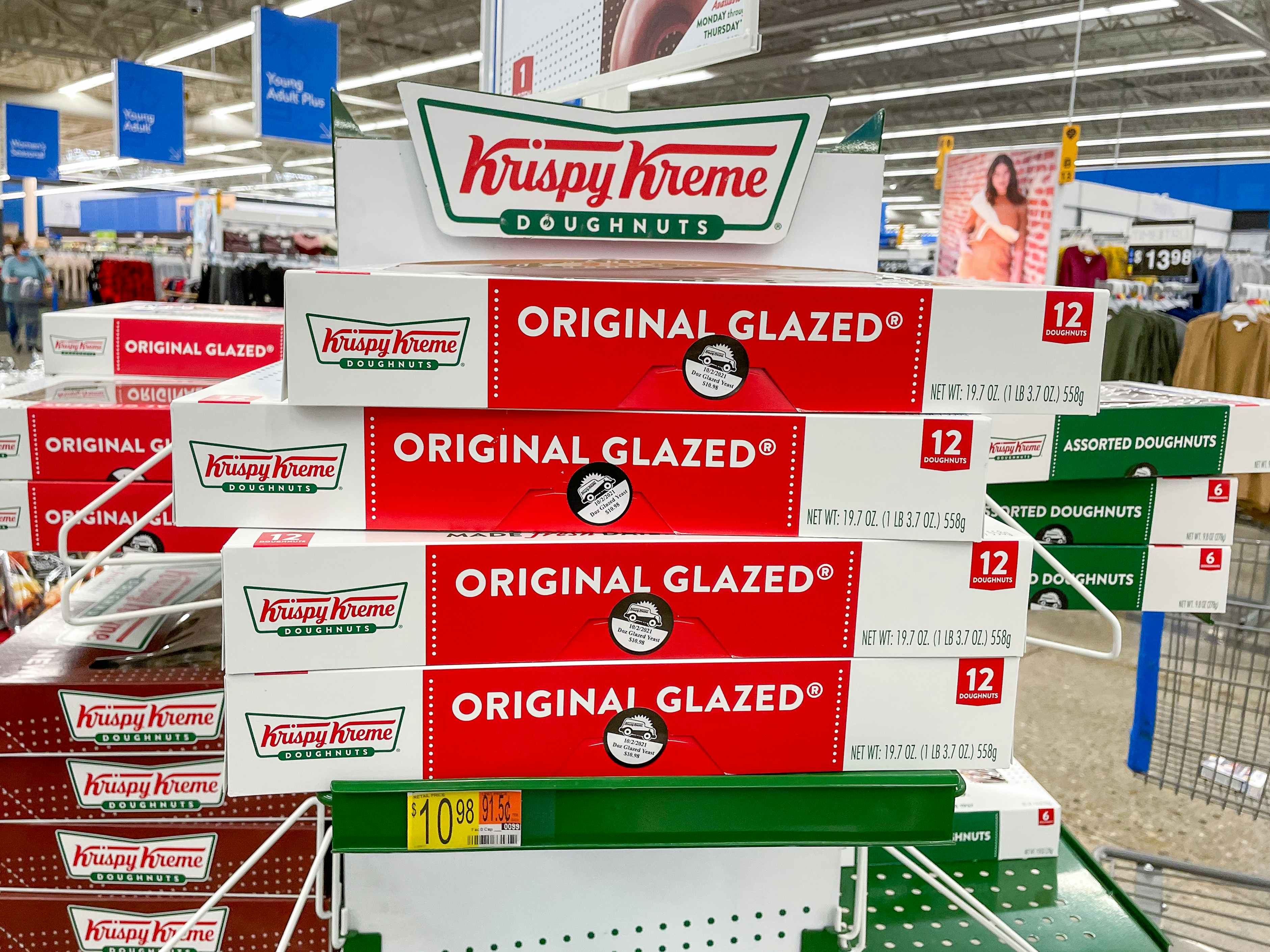 A stack of boxed dozens of Krispy Kreme original glazed doughnuts on a shelf at Walmart.