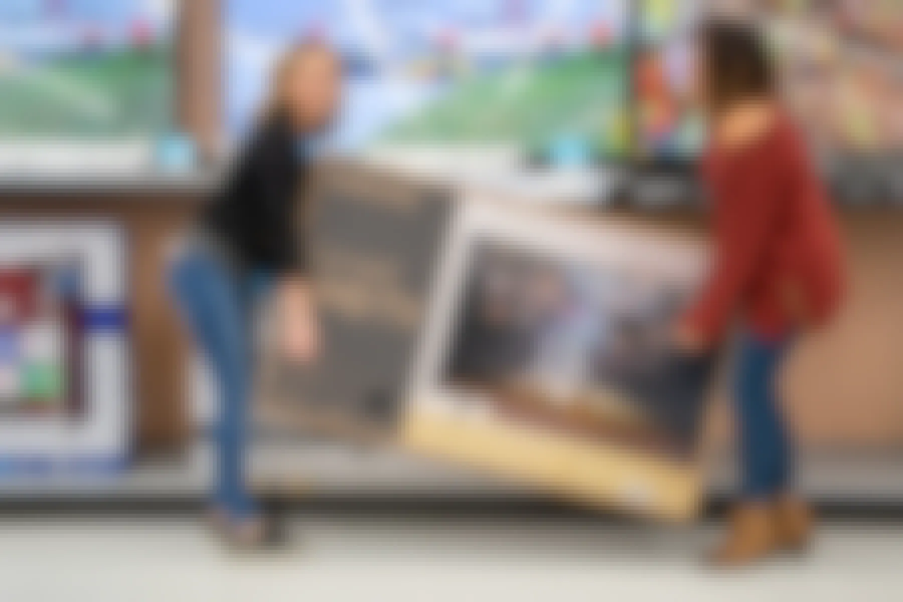 Two women picking up a Samsung Curved TV inside the electronics section at Walmart
