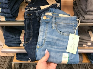 hand grabbing universal thread women's jeans off a target shelf