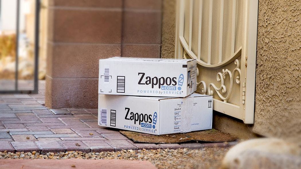 Two Zappos boxes stacked on a front porch.