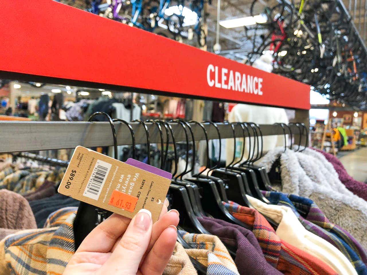 A person's hand holding up a tag on clearance item in store at REI
