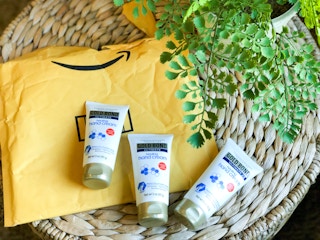 three bottles of gold bond healing hand cream on a wicker table with an amazon package