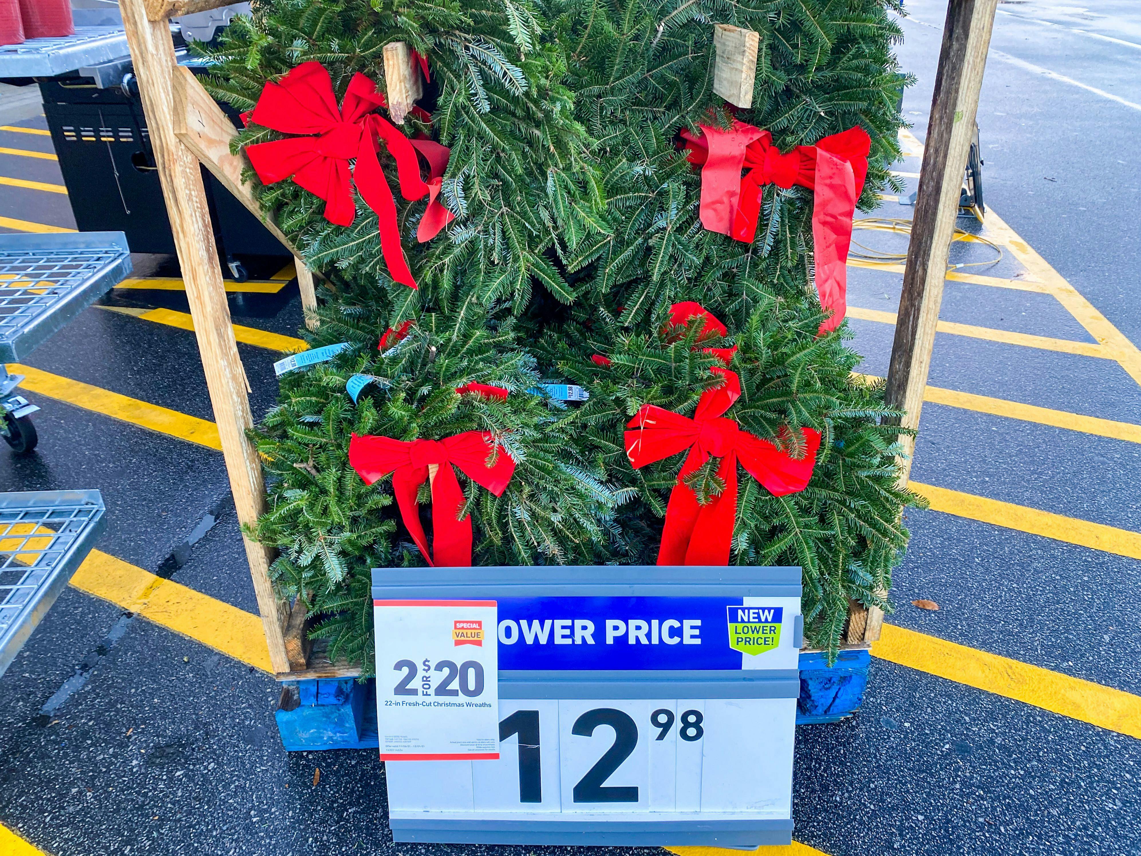 Holiday wreaths on display in front of Lowe's with a sale sign that says, "2 for $20