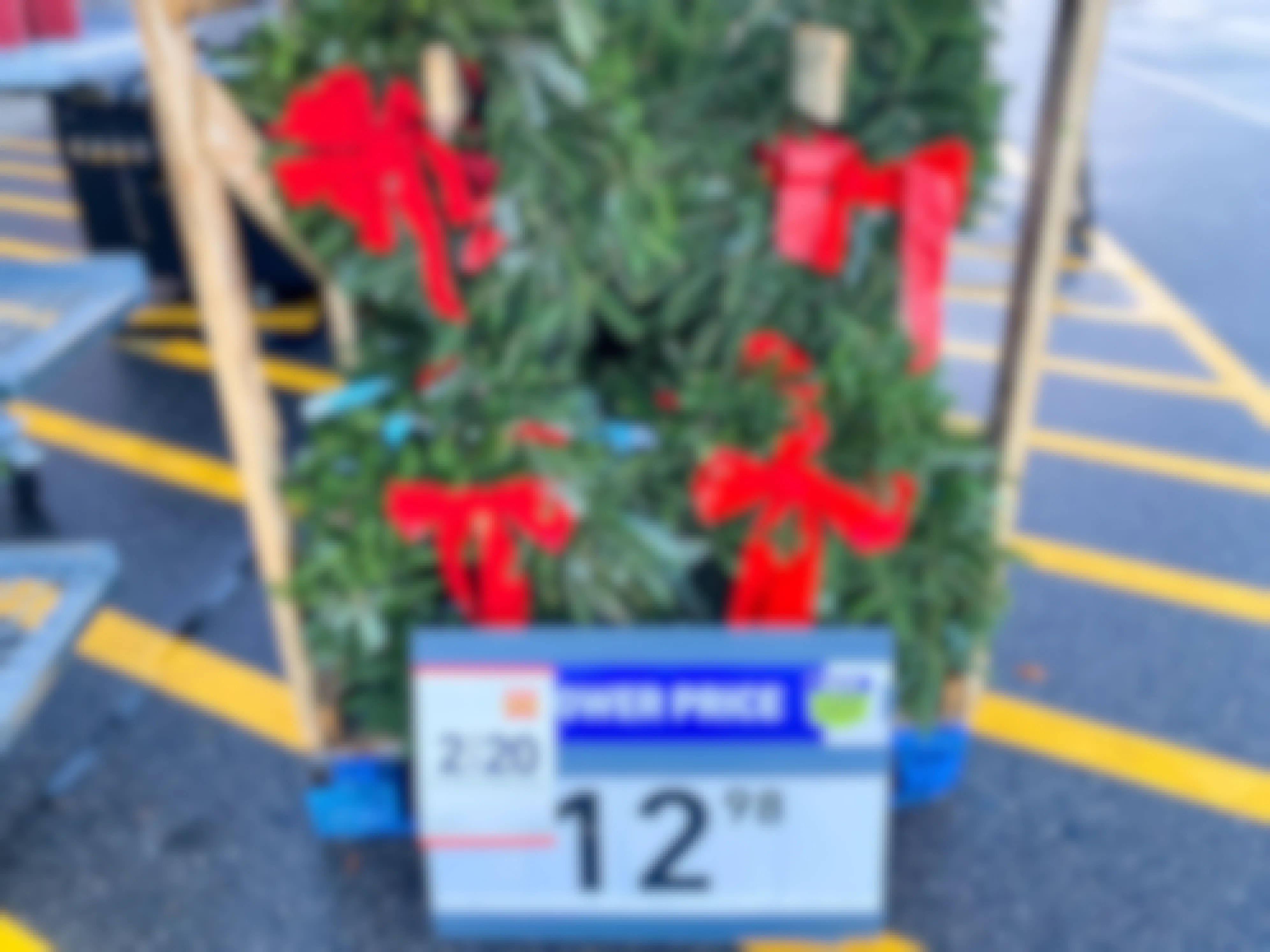 Holiday wreaths on display in front of Lowe's with a sale sign that says, "2 for $20
