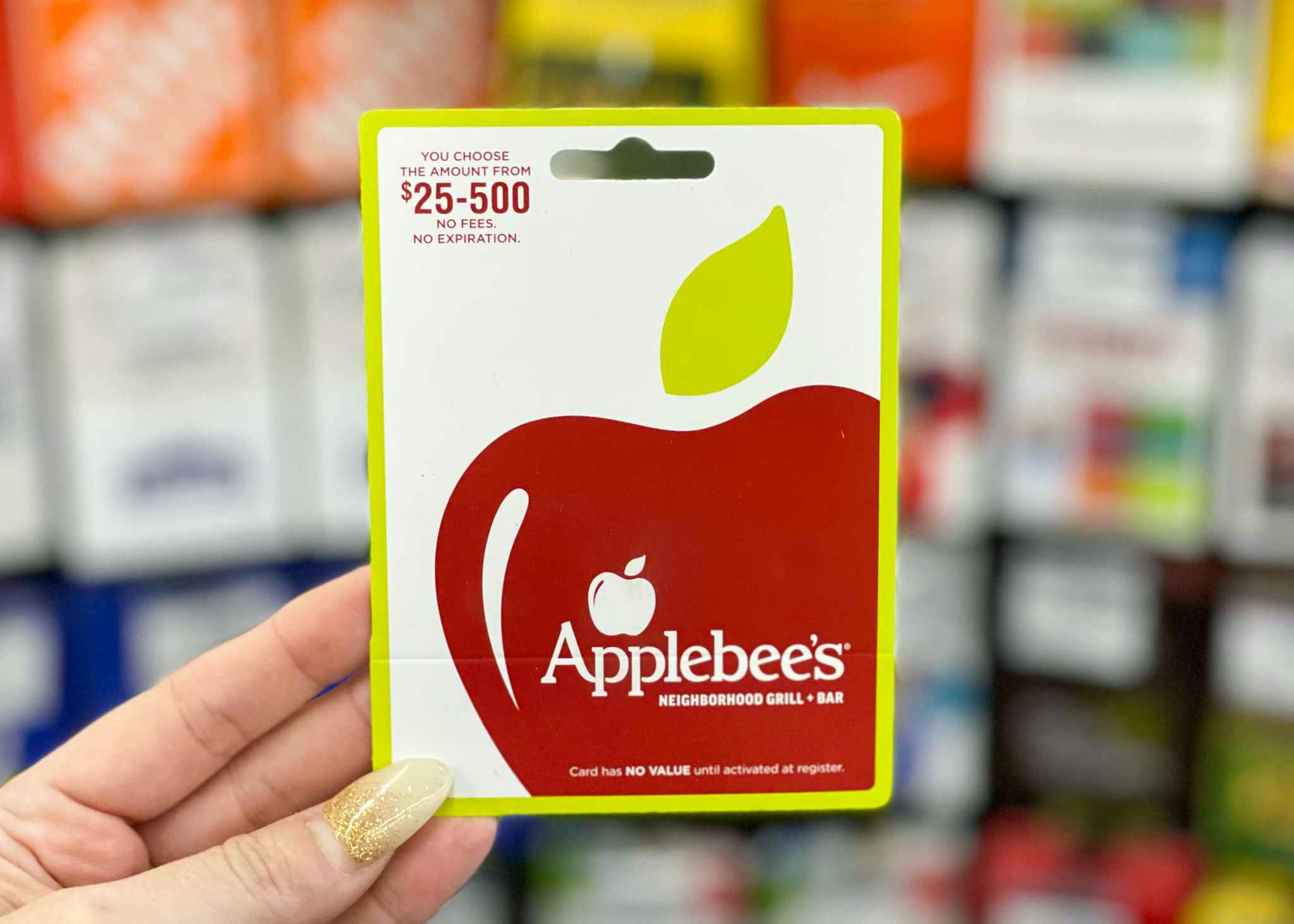 woman holding up an applebee's gift card for $25-$500