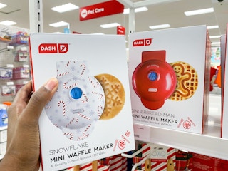 hand holding a dash snowflake waffle maker in front of a gingerbread waffle maker at target