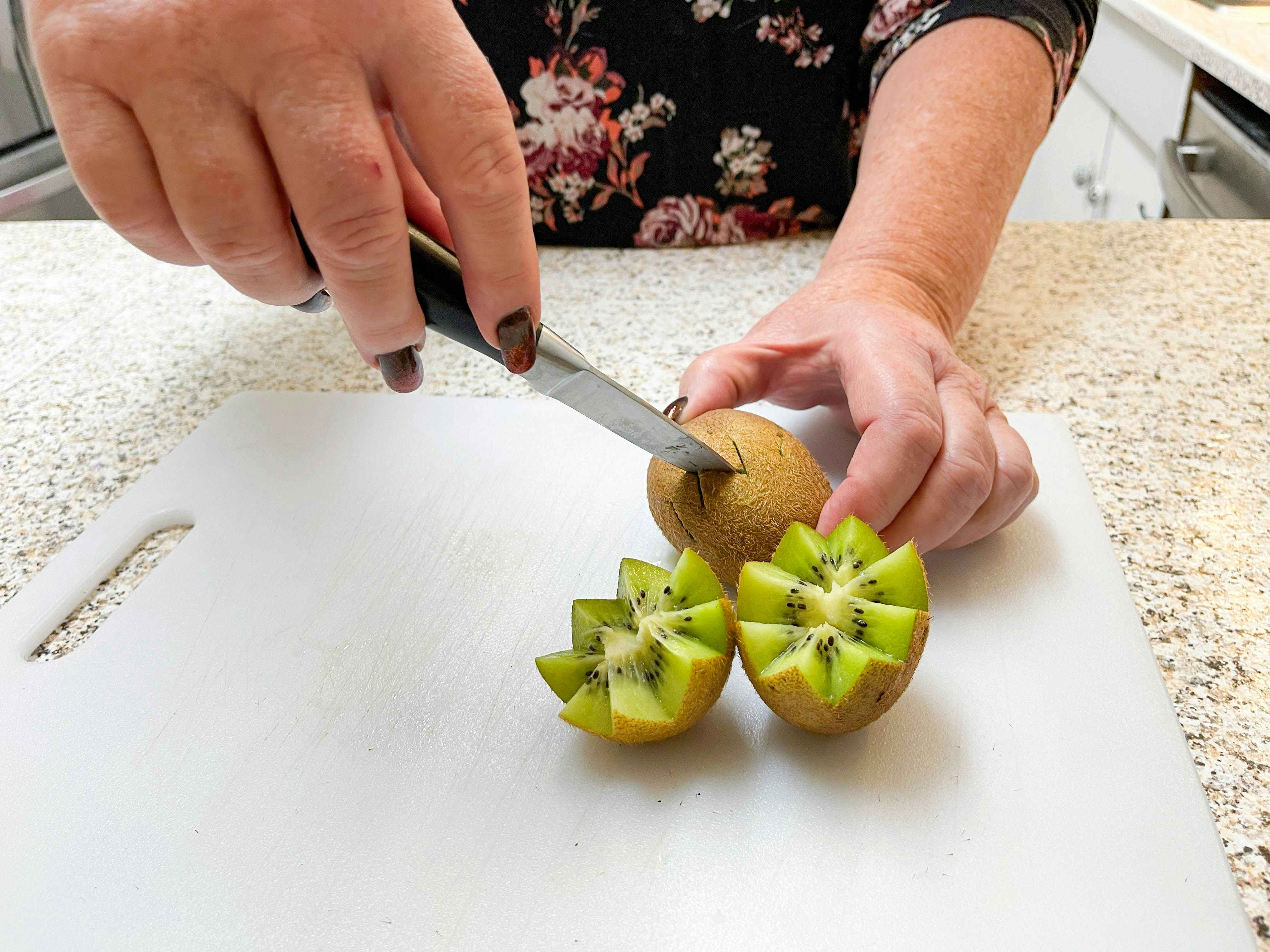 woman cutting kiwi in zig zag 