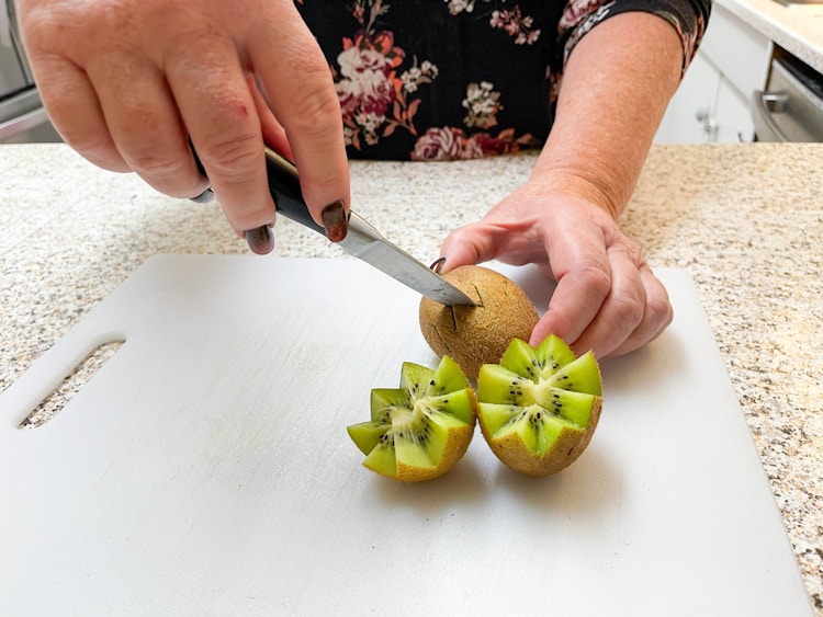 woman cutting kiwi in zig zag 