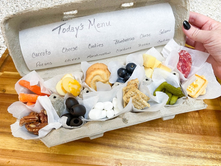 little boy eating cheese snack plate in an egg carton 