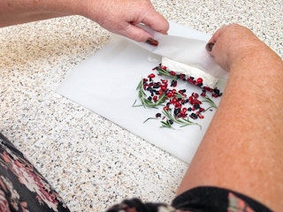 woman rolling goat cheese in rosemary & dried fruits with wax paper 