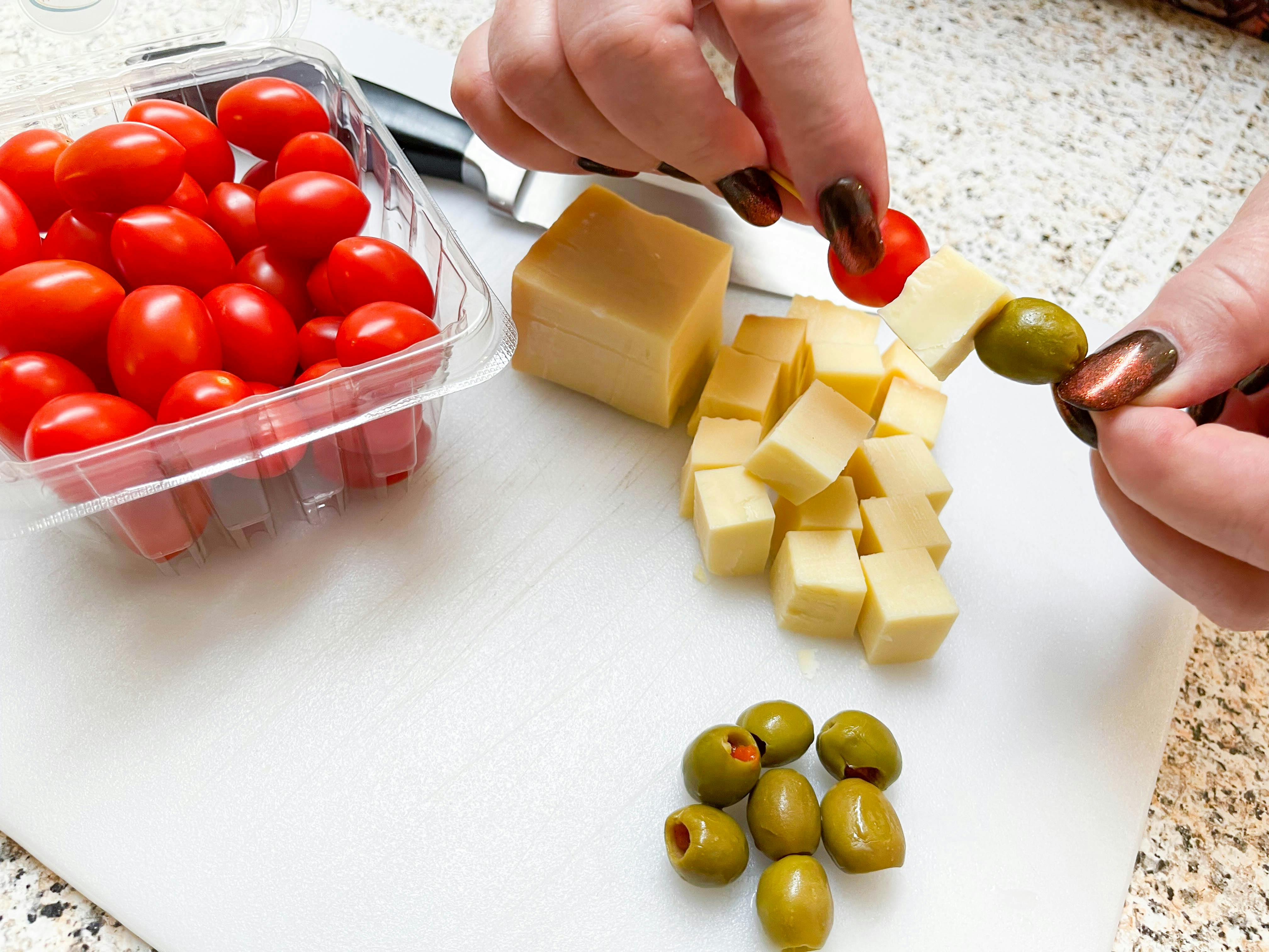 putting cheese, olives and tomates on toothpicks 