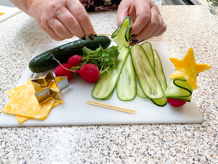 making christmas trees out of sliced cucumber, radish and cheese 