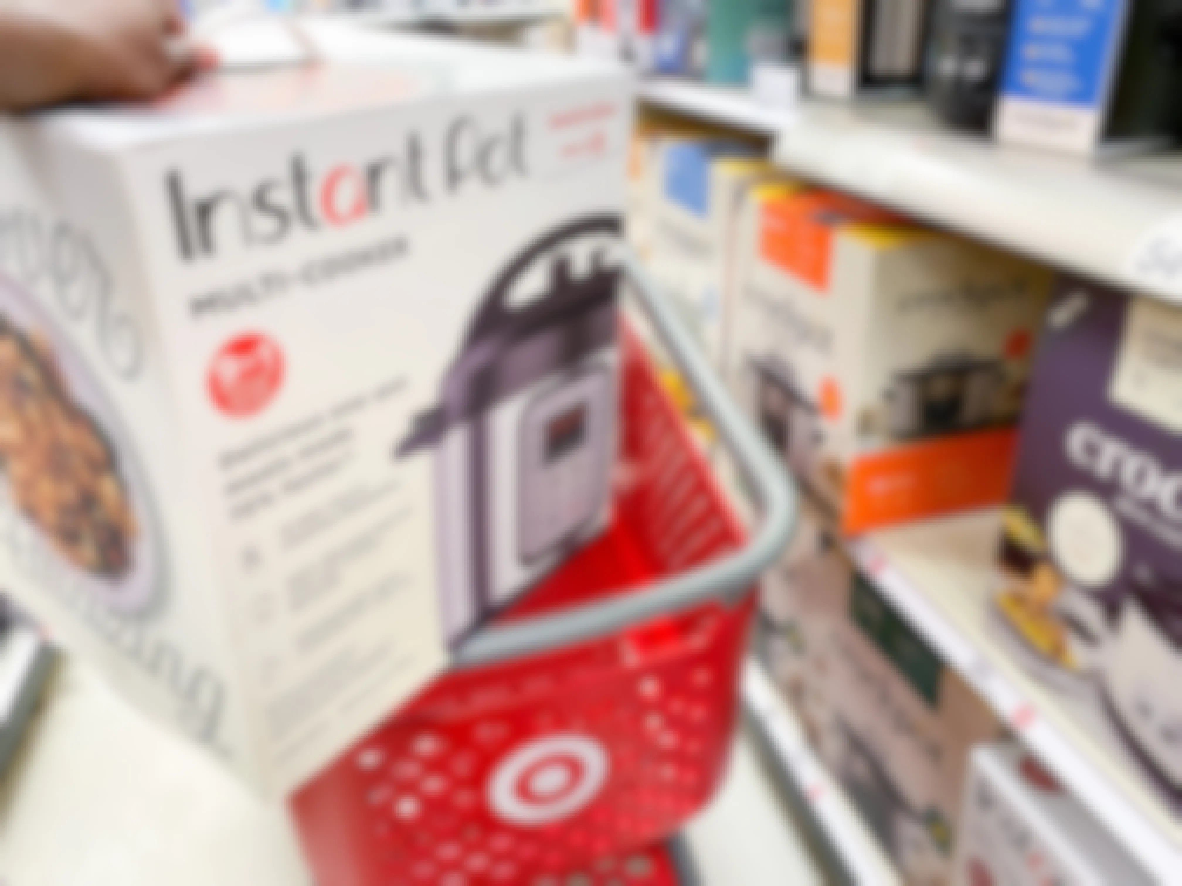 A person putting an Instant Pot 6-Quart 9-in-1 Bundle in its box into a Target shopping cart.