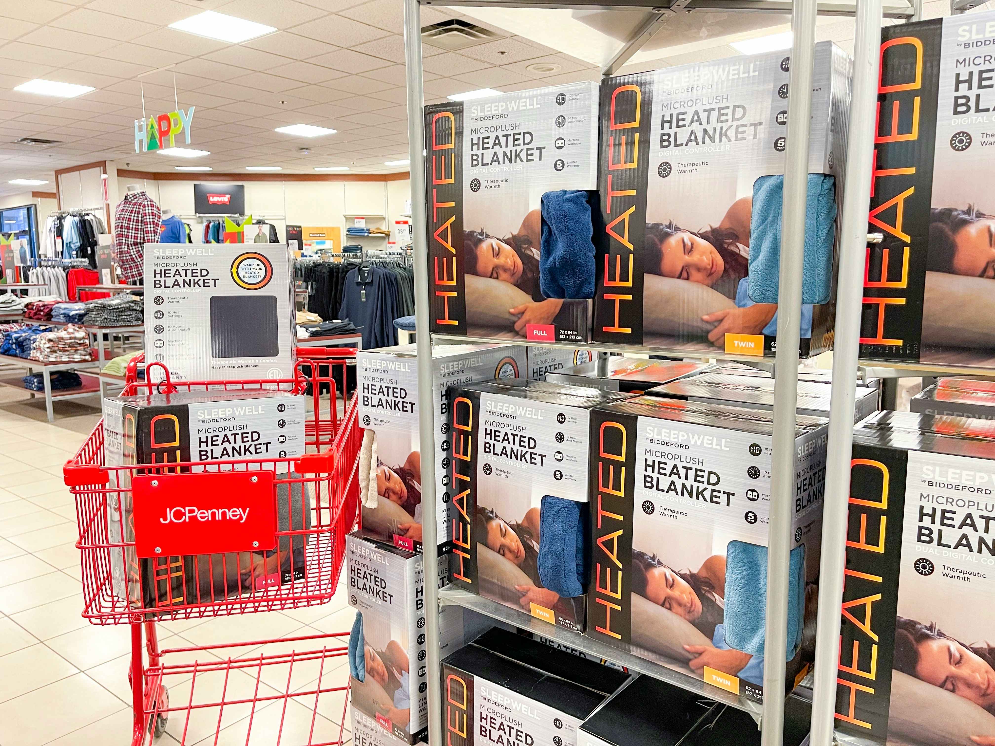 Boxes of heated blankets in a JCPenney shopping cart parked next to a display of more heated blankets inside JCPenney.