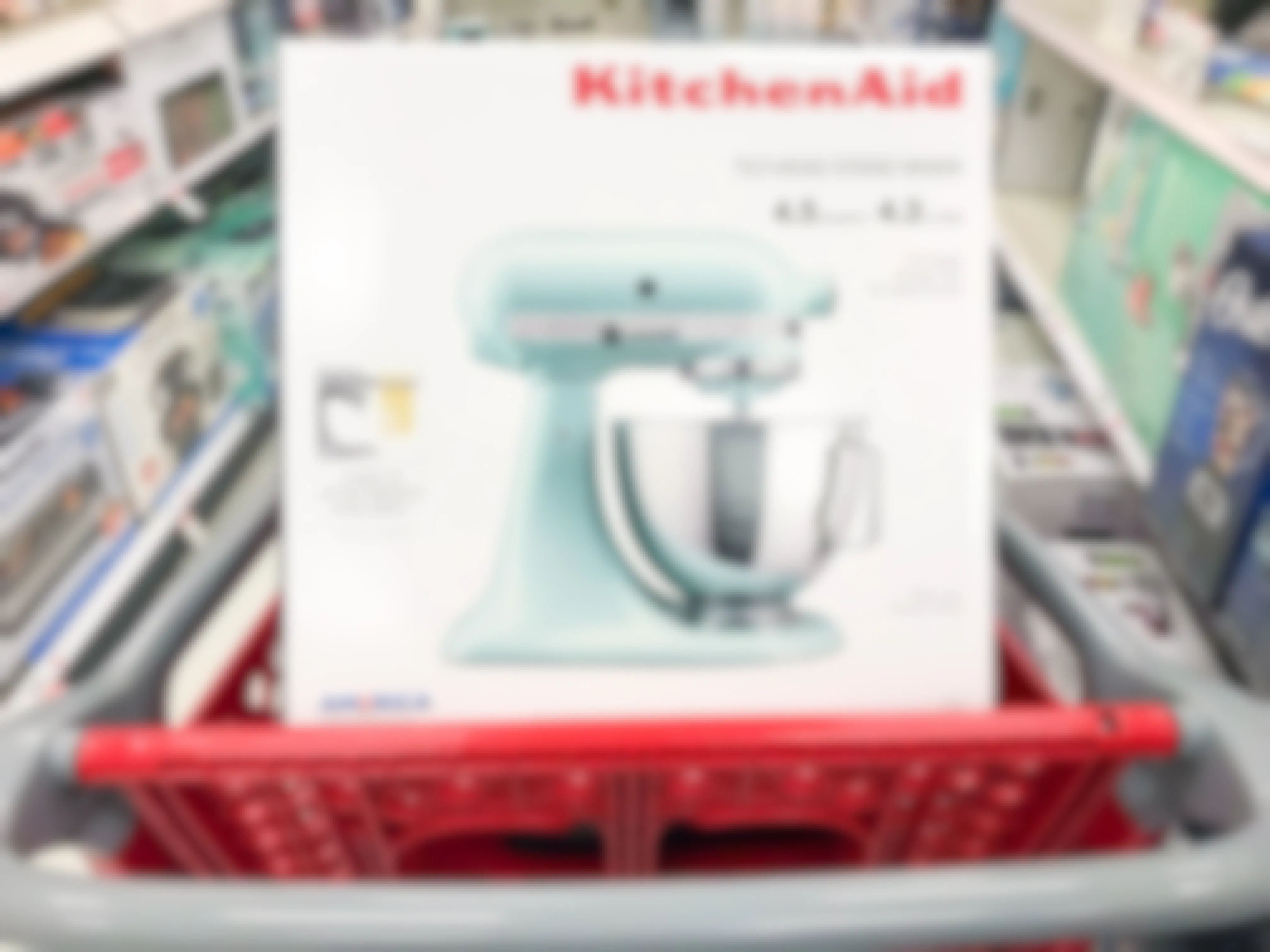 A KitchenAid stand mixer box sitting in the basket of a Target shopping cart in the small kitchen appliance aisle at Target..