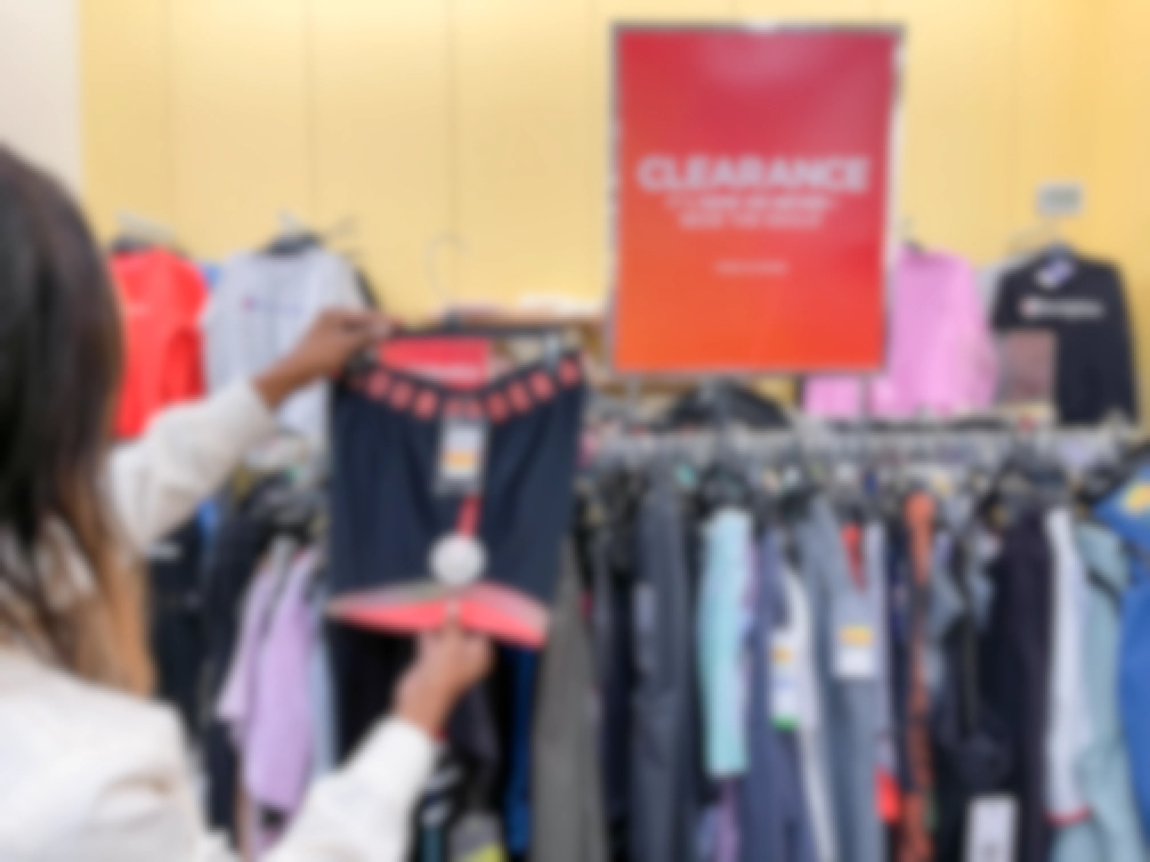 A woman holding a pair of Under Armour shorts next to a clearance sign