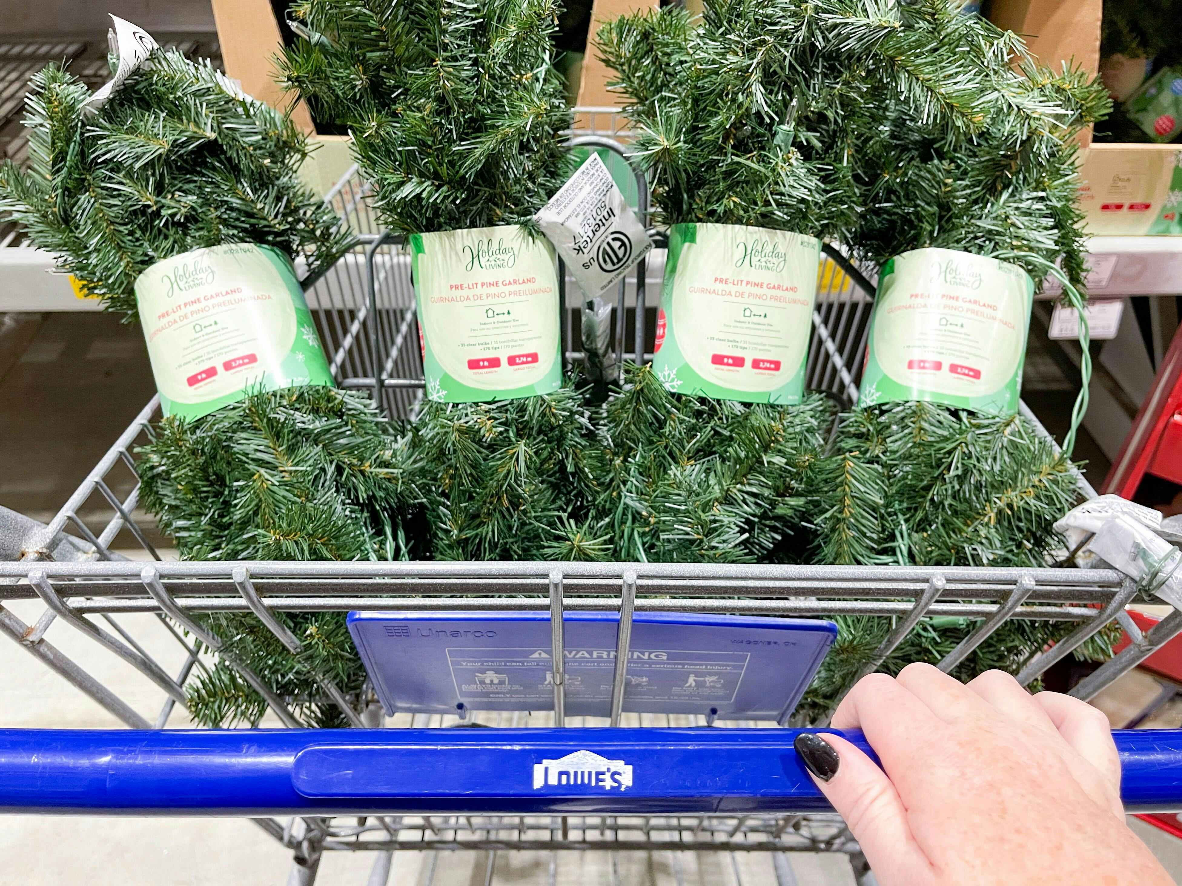 four rolls of christmas garland in a lowe's shopping cart