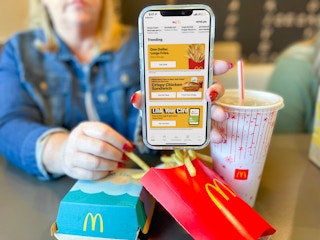 women holding cellphone with mcdonalds app in front of meal