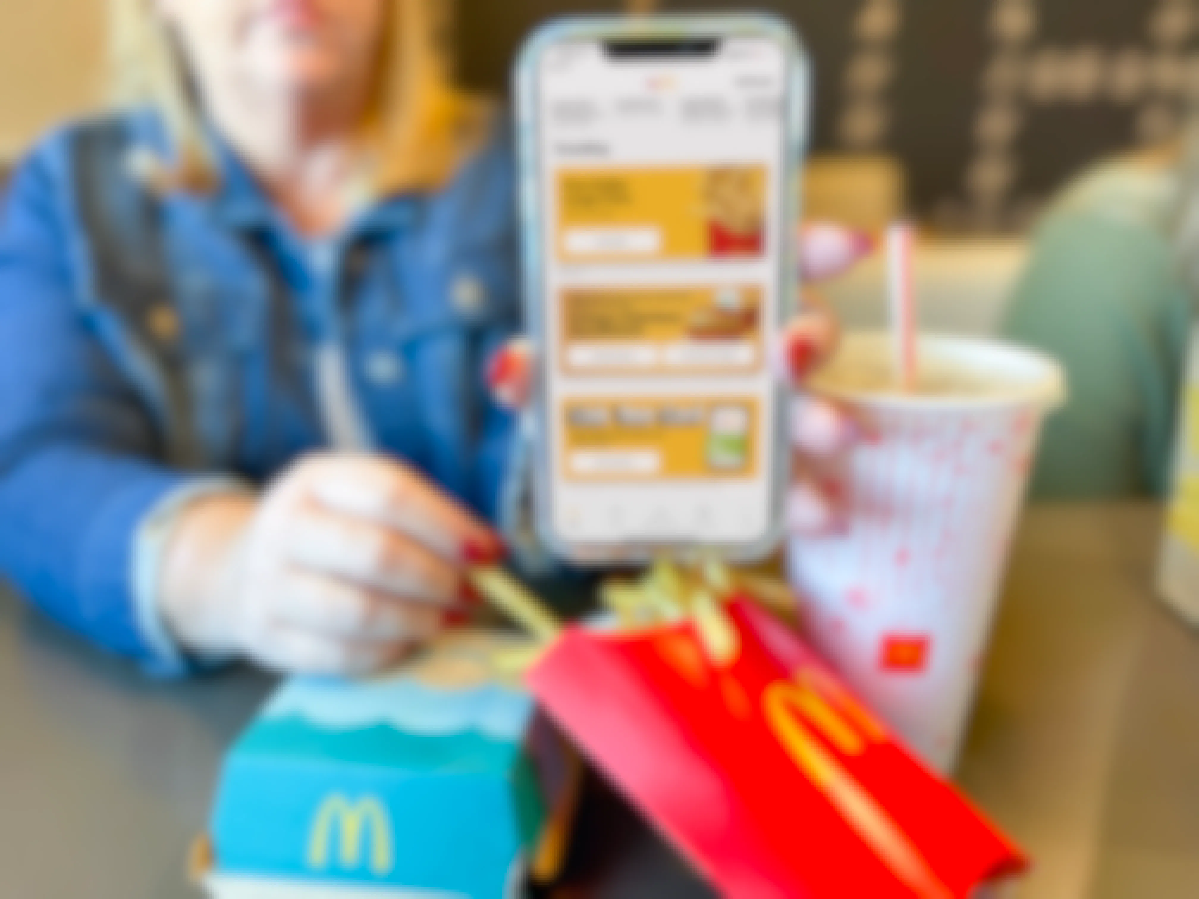 chick-fil-a- vs. mcdonald's - women holding cellphone with mcdonalds app in front of meal