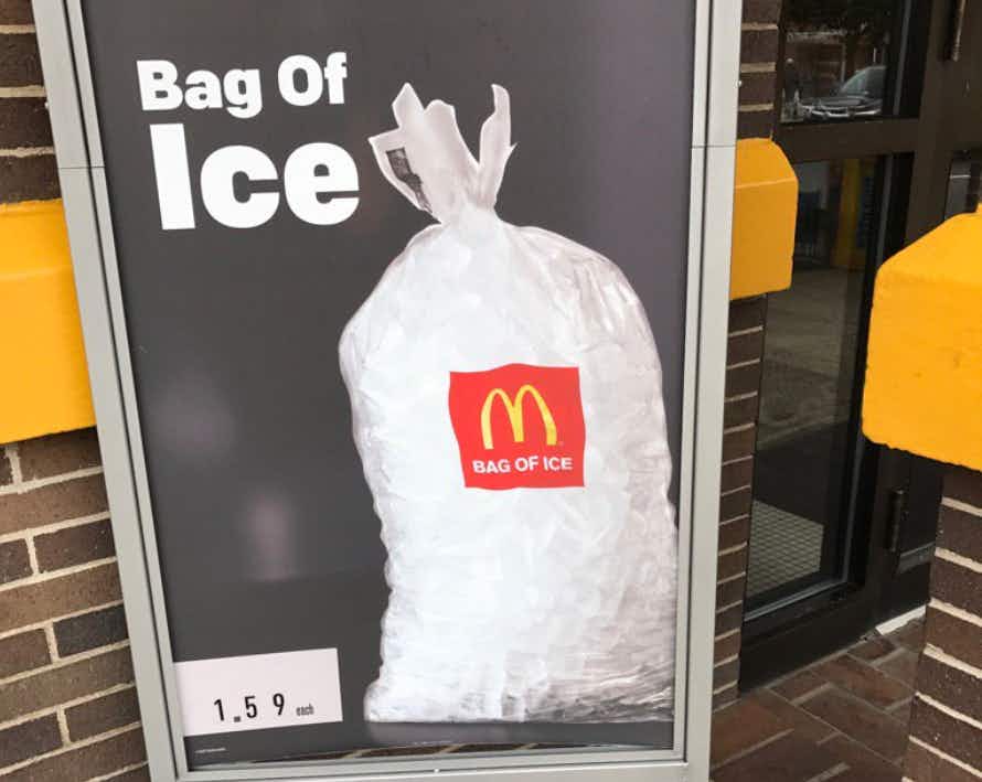 A sign outside of a McDonald's restaurant advertising bags of ice available for purchase.