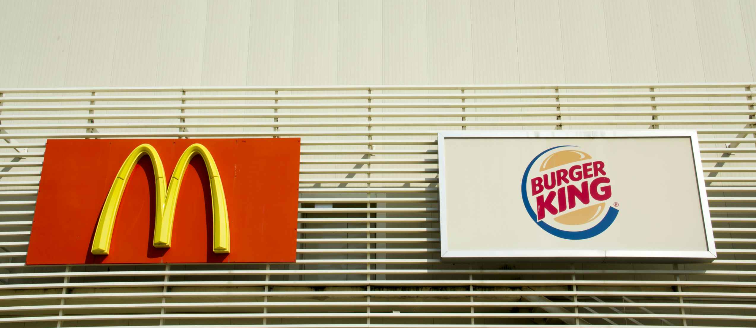 McDonald's and Burger King signs hanging side by side.
