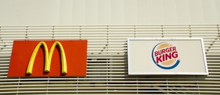 McDonald's and Burger King signs hanging side by side.