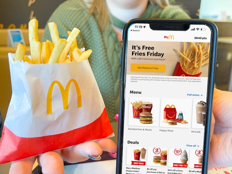 person holding cellphone with mcdonalds app and french fries