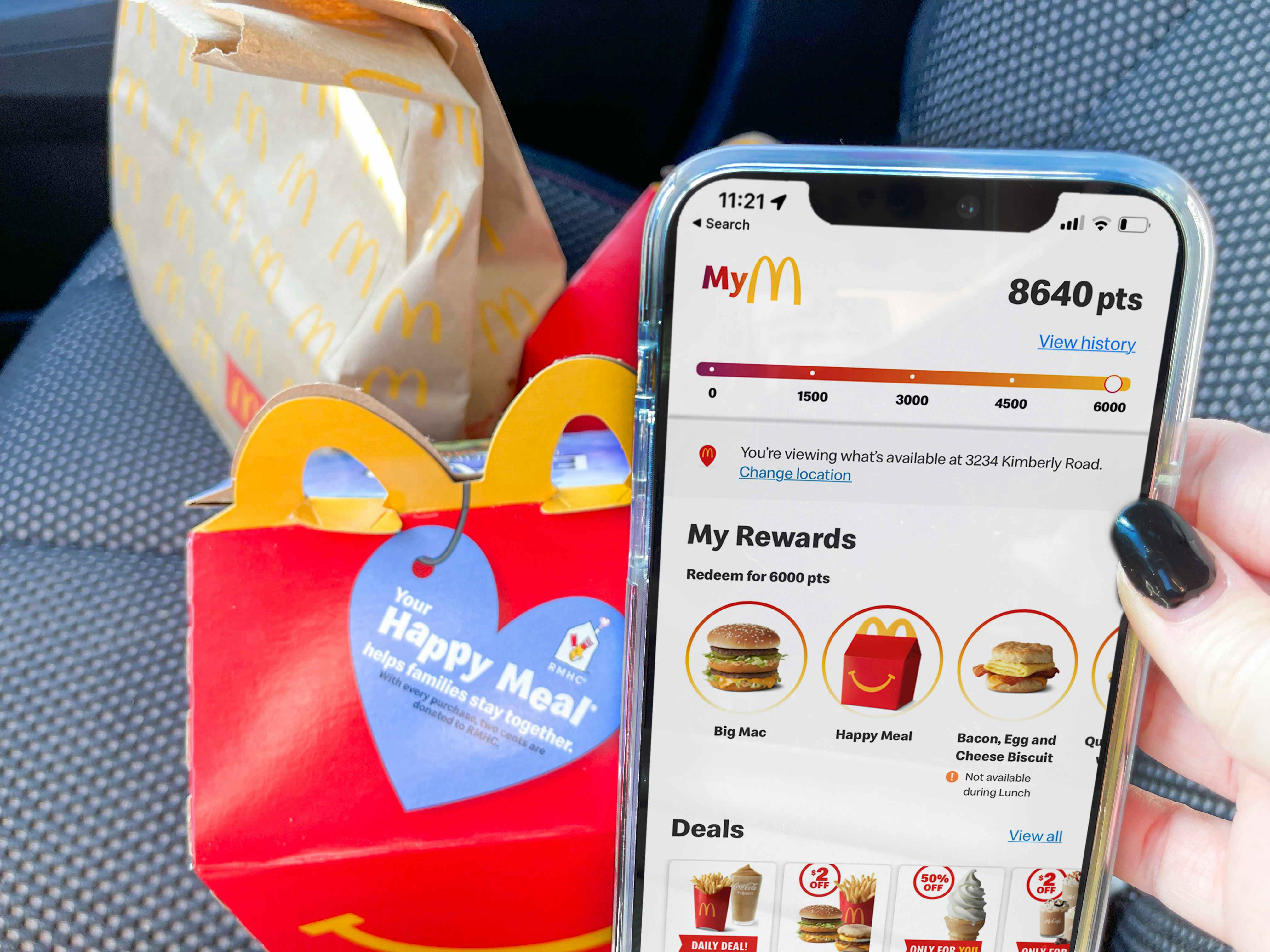 person holding phone with mcdonalds app next to happy meal