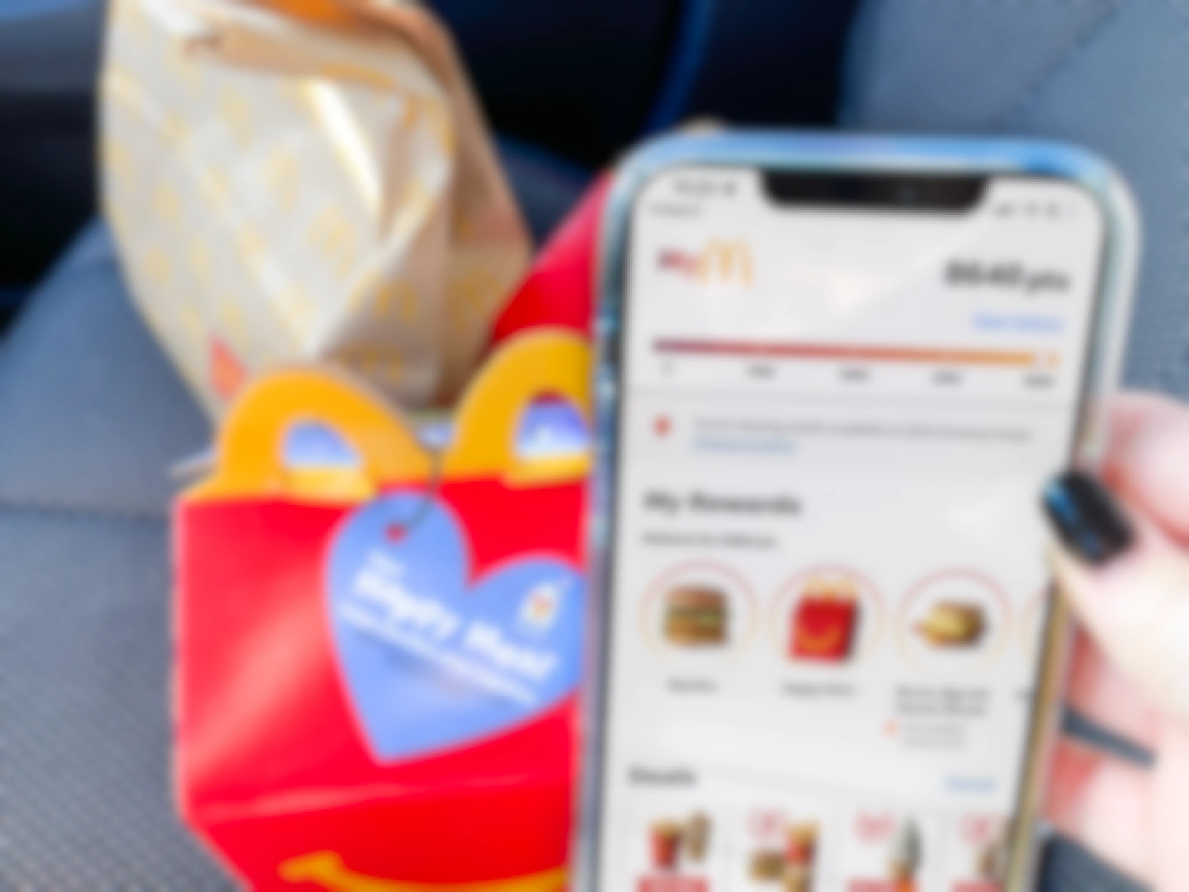 women holding cellphone with mcdonalds app next to happy meal