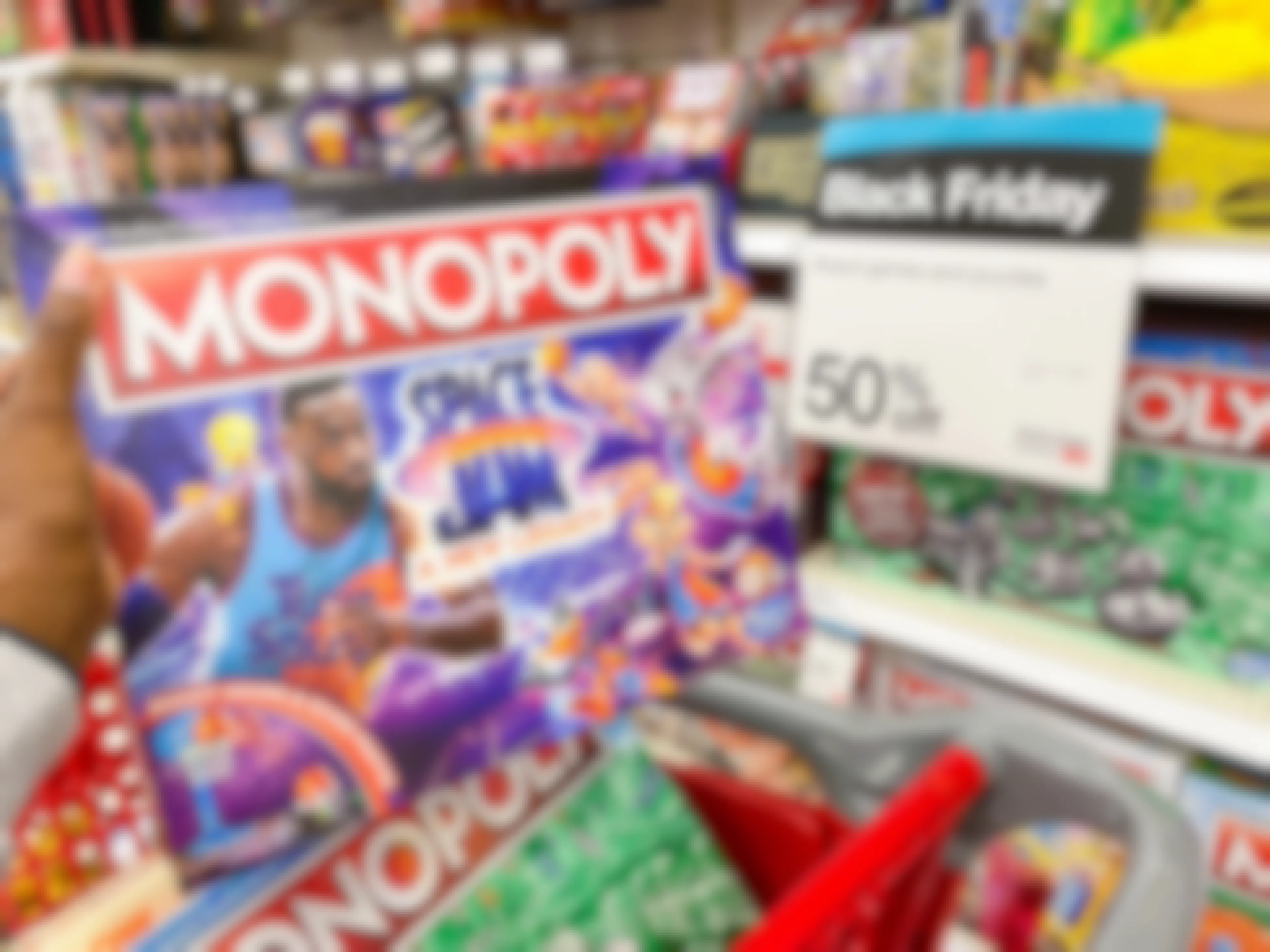 Monopoly games in a shopping cart next to a sign that says 50% off for Black Friday
