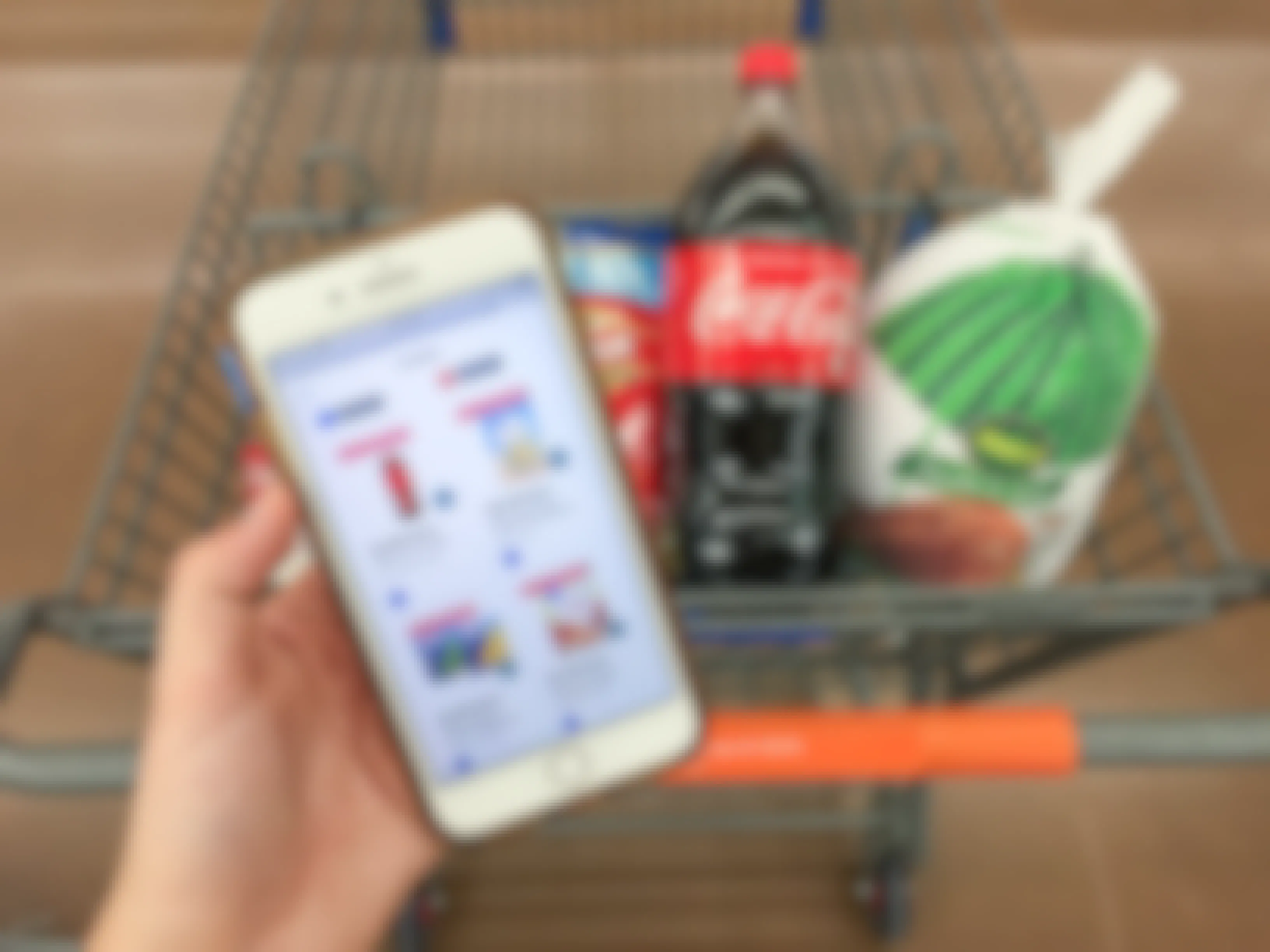 hand holding iphone with ibotta offers on phone with coke and turkey in walmart shopping cart