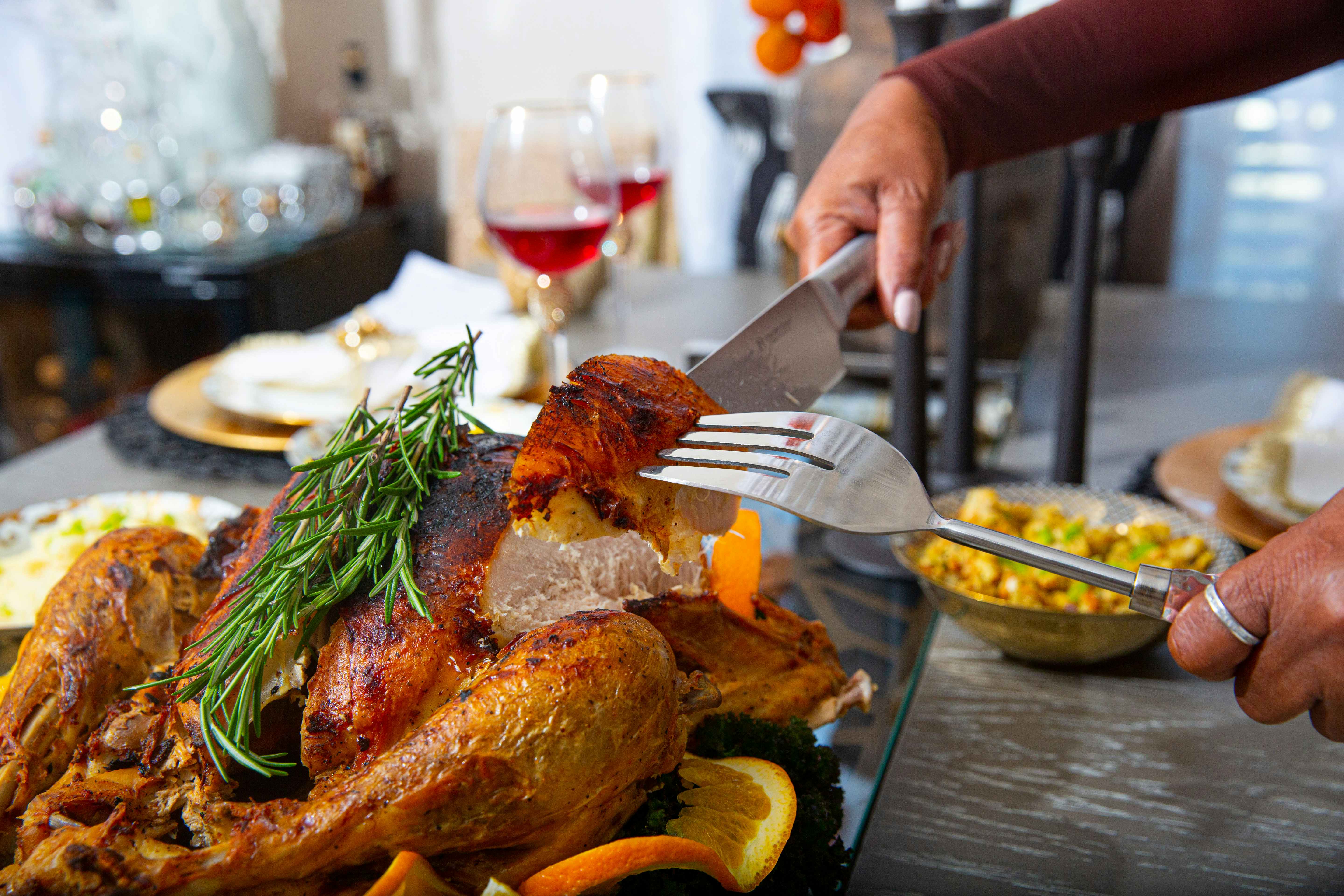 Person holding a slice of turkey with a knife and large fork