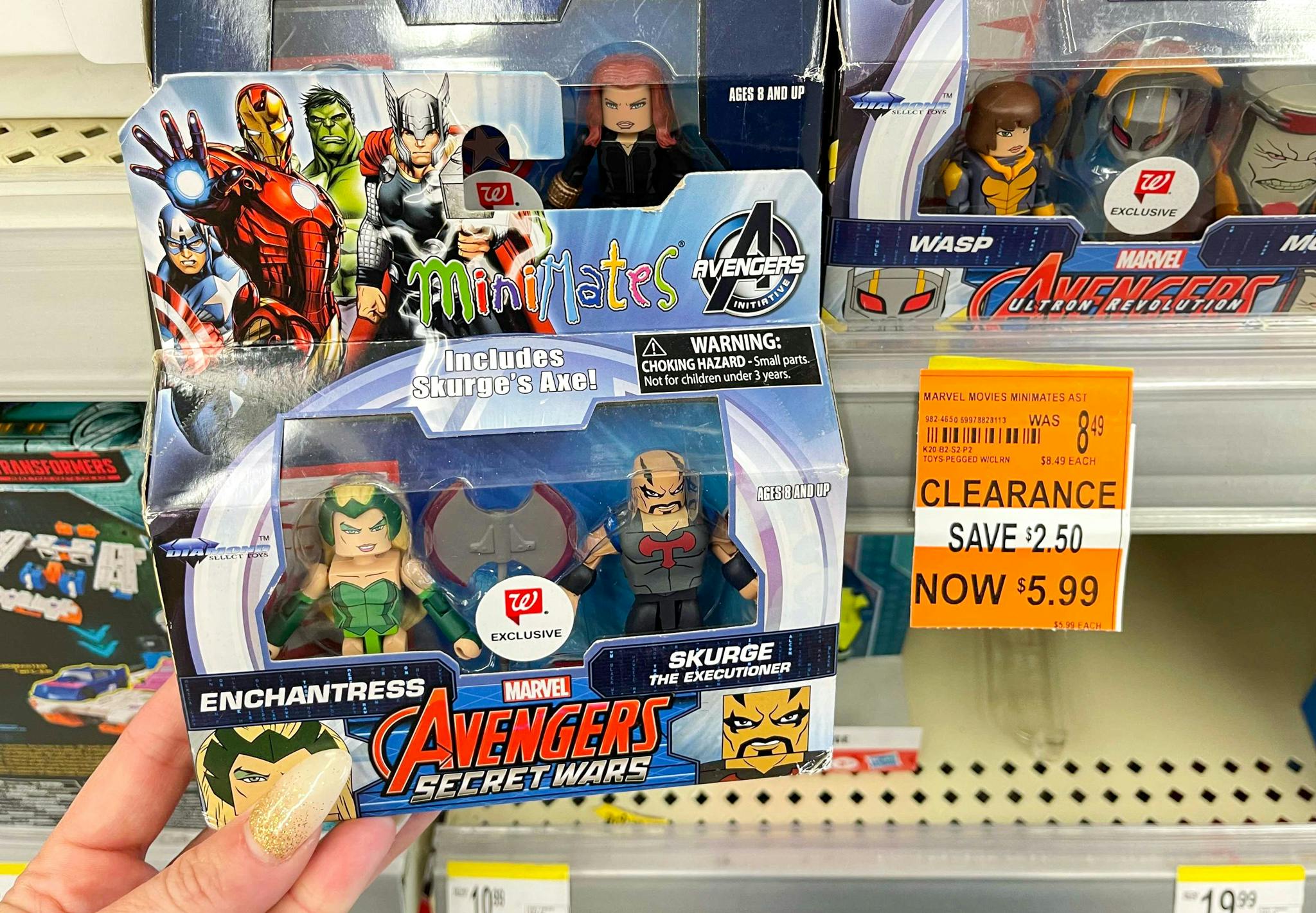 A person's hand holding a clearance Marvel toy next to a clearance sticker on a shelf at Walgreens.