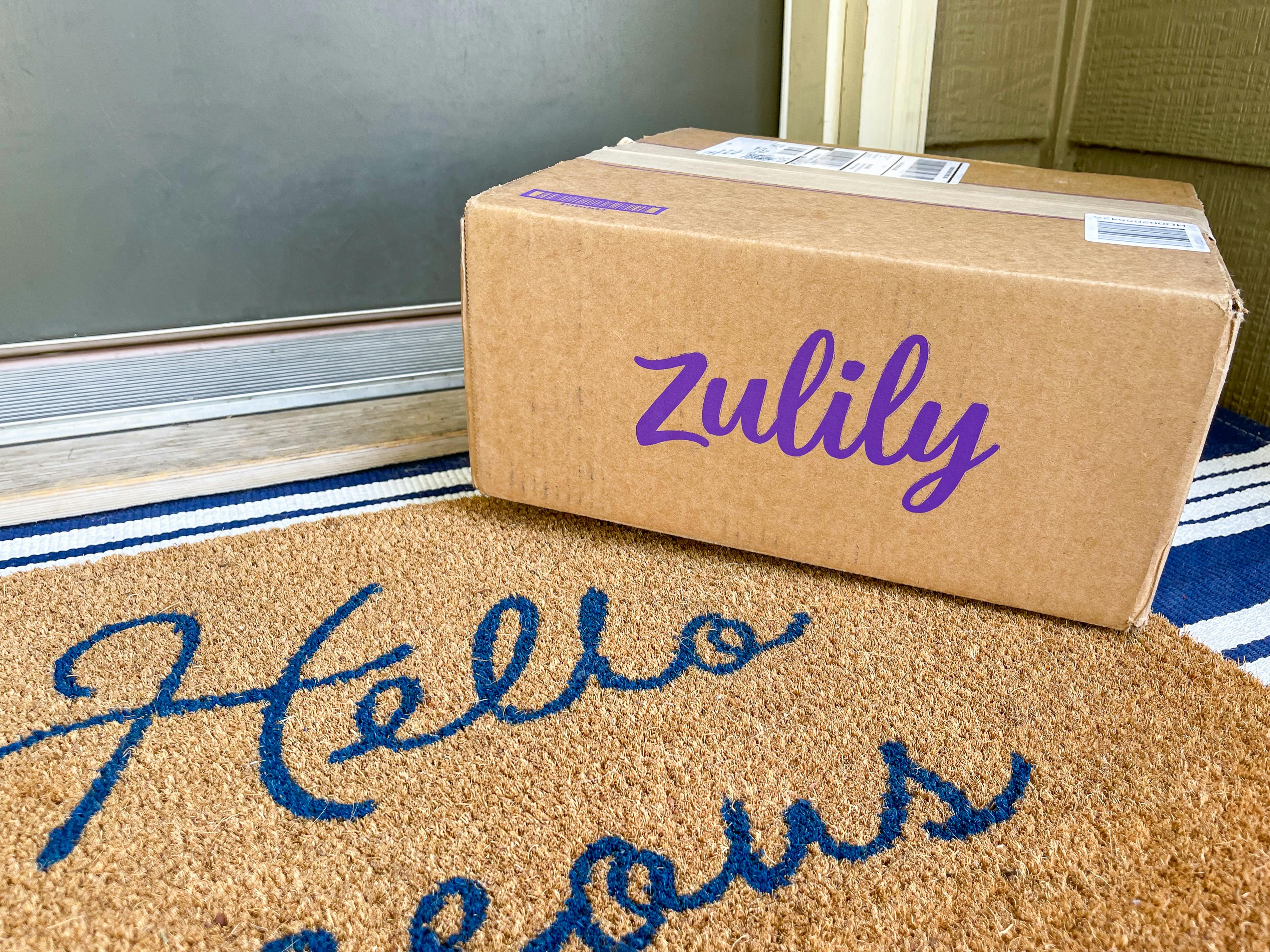 A Zulily box sitting on a front porch in front of someone's front door.