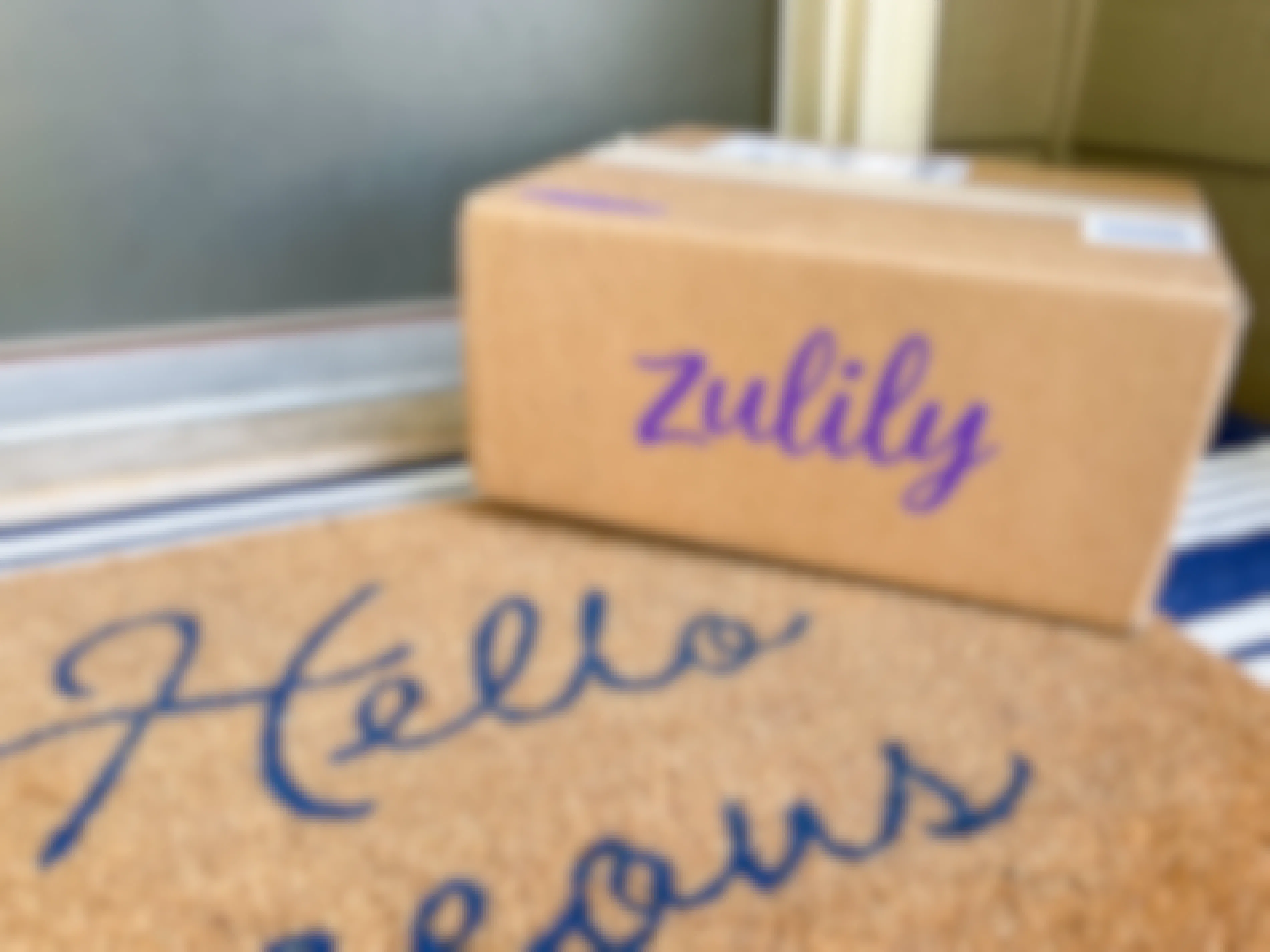 A Zulily box sitting on a front porch in front of someone's front door.