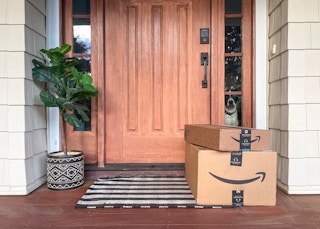Two amazon boxes, stacked on top of each other, sitting in front of a front door.