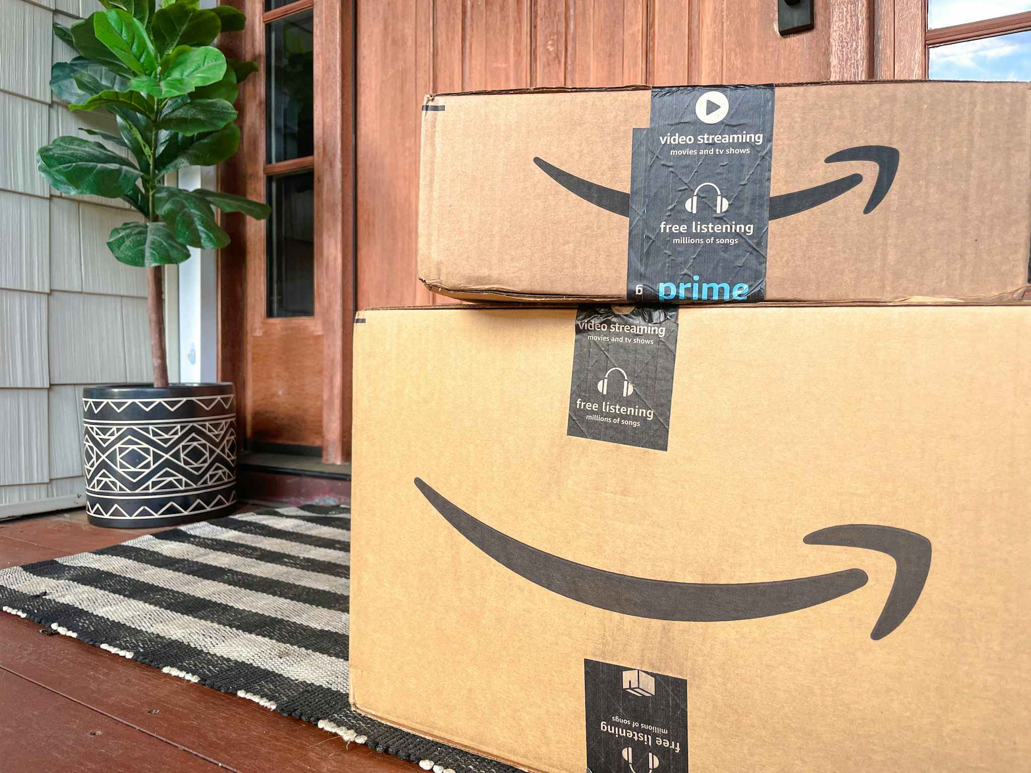 Two amazon boxes, stacked on top of each other, sitting in front of a front door.