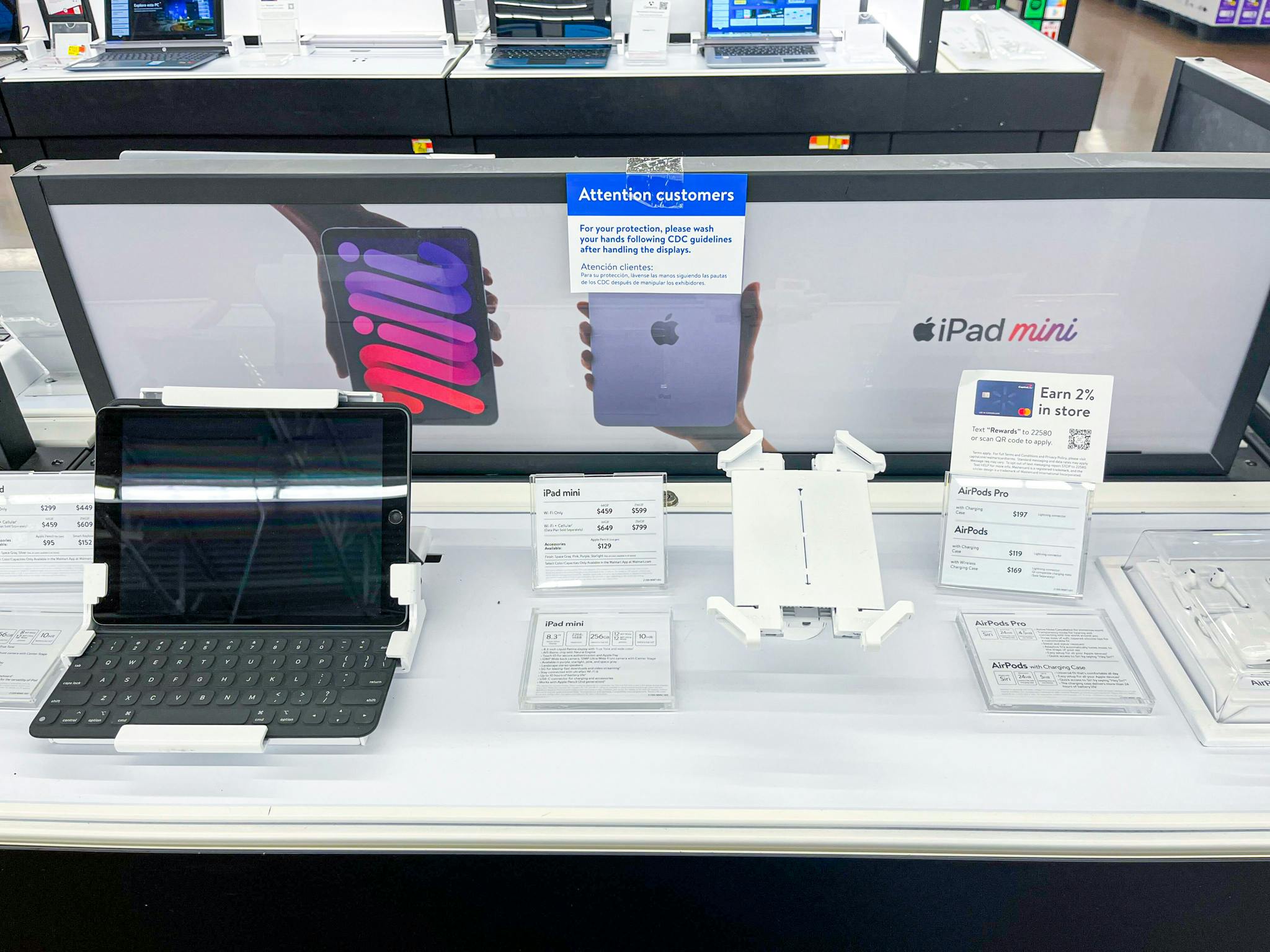 An apple ipad on display in store with an iplad mini signage behind display.
