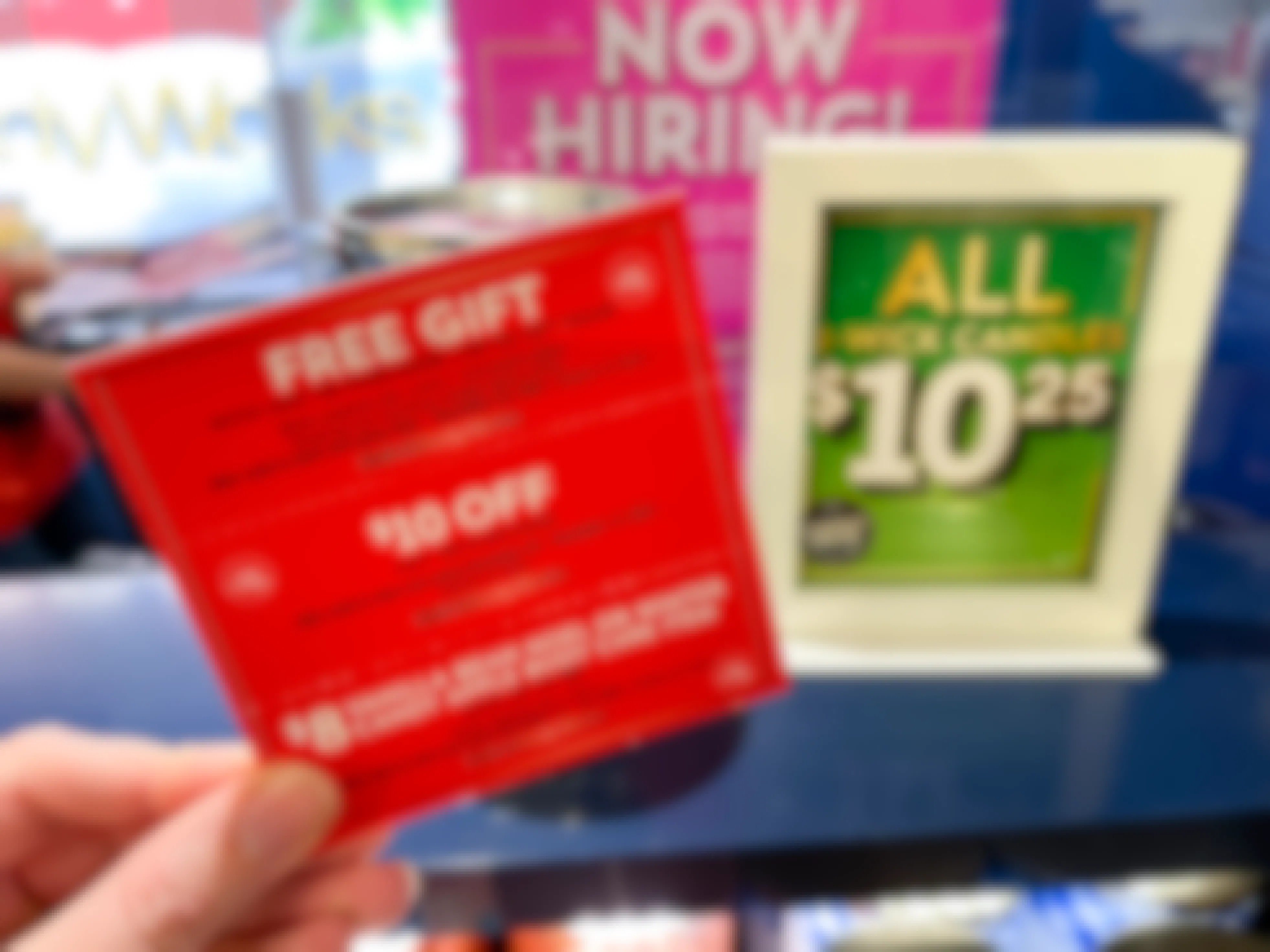 A woman holding bath and body works coupons next to a candle day sale sign