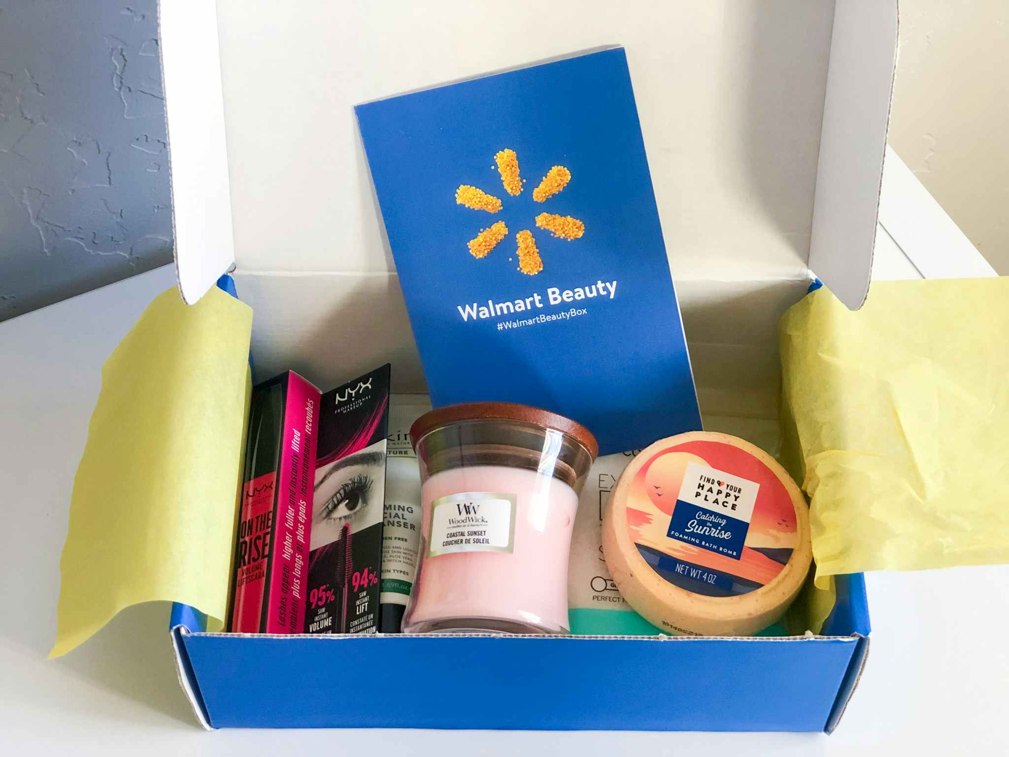 A Walmart beauty box, with makeup and other beauty products, sitting open on a table.